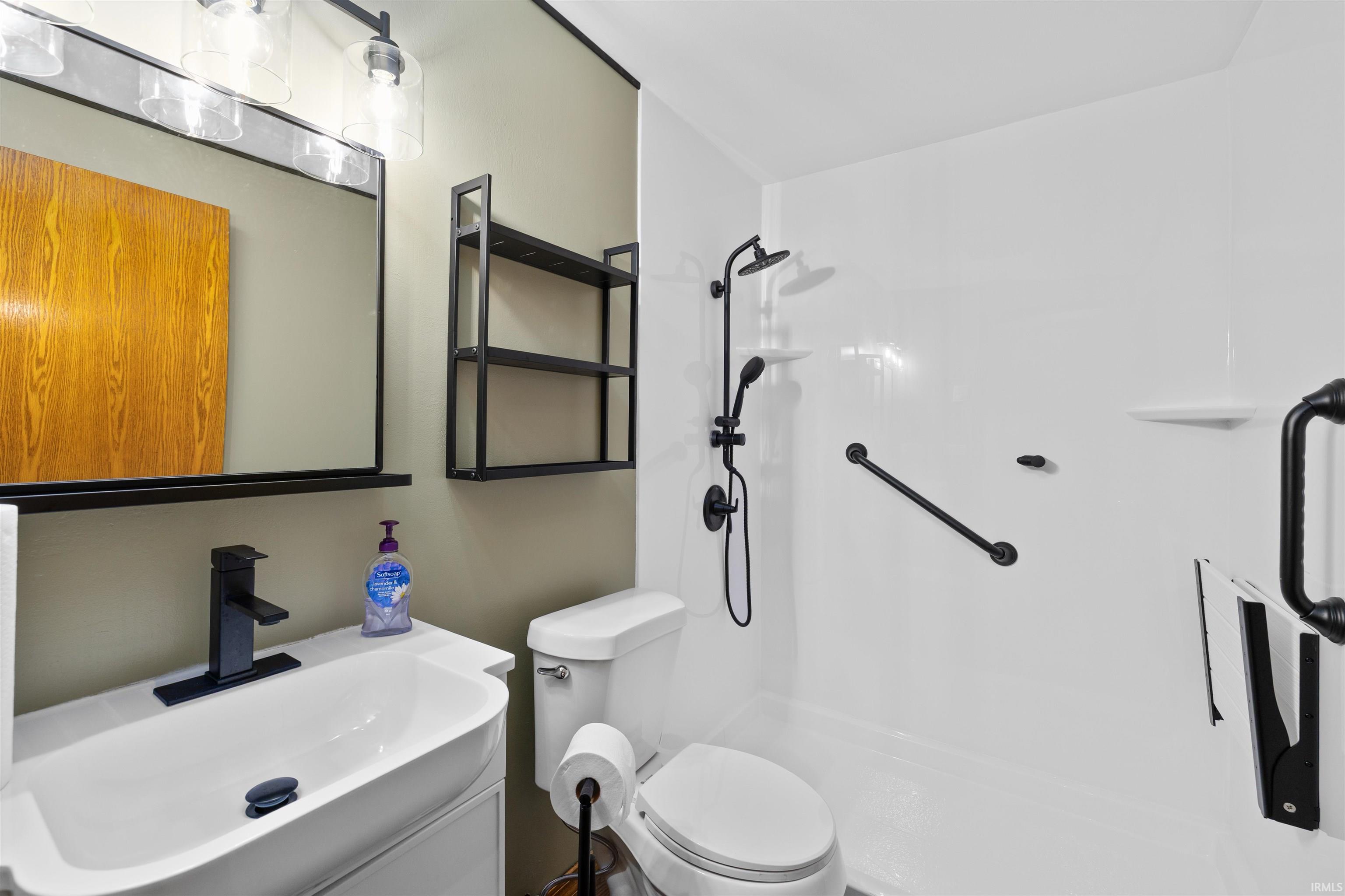 Modern bathroom featuring a single vanity with a sleek black faucet, a framed mirror, and built-in shelving