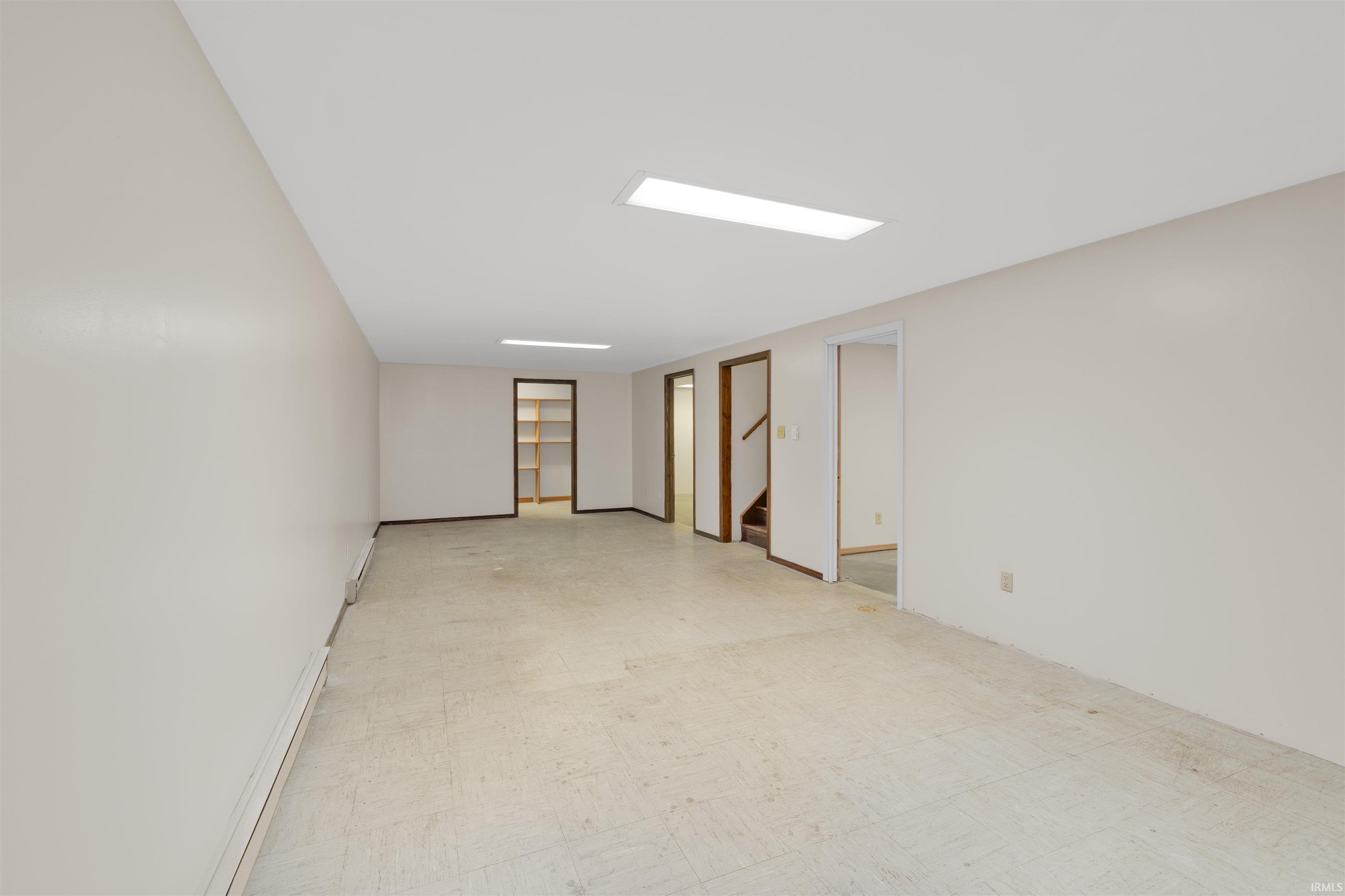 Spacious room with light-toned walls, recessed lighting, and multiple doorways