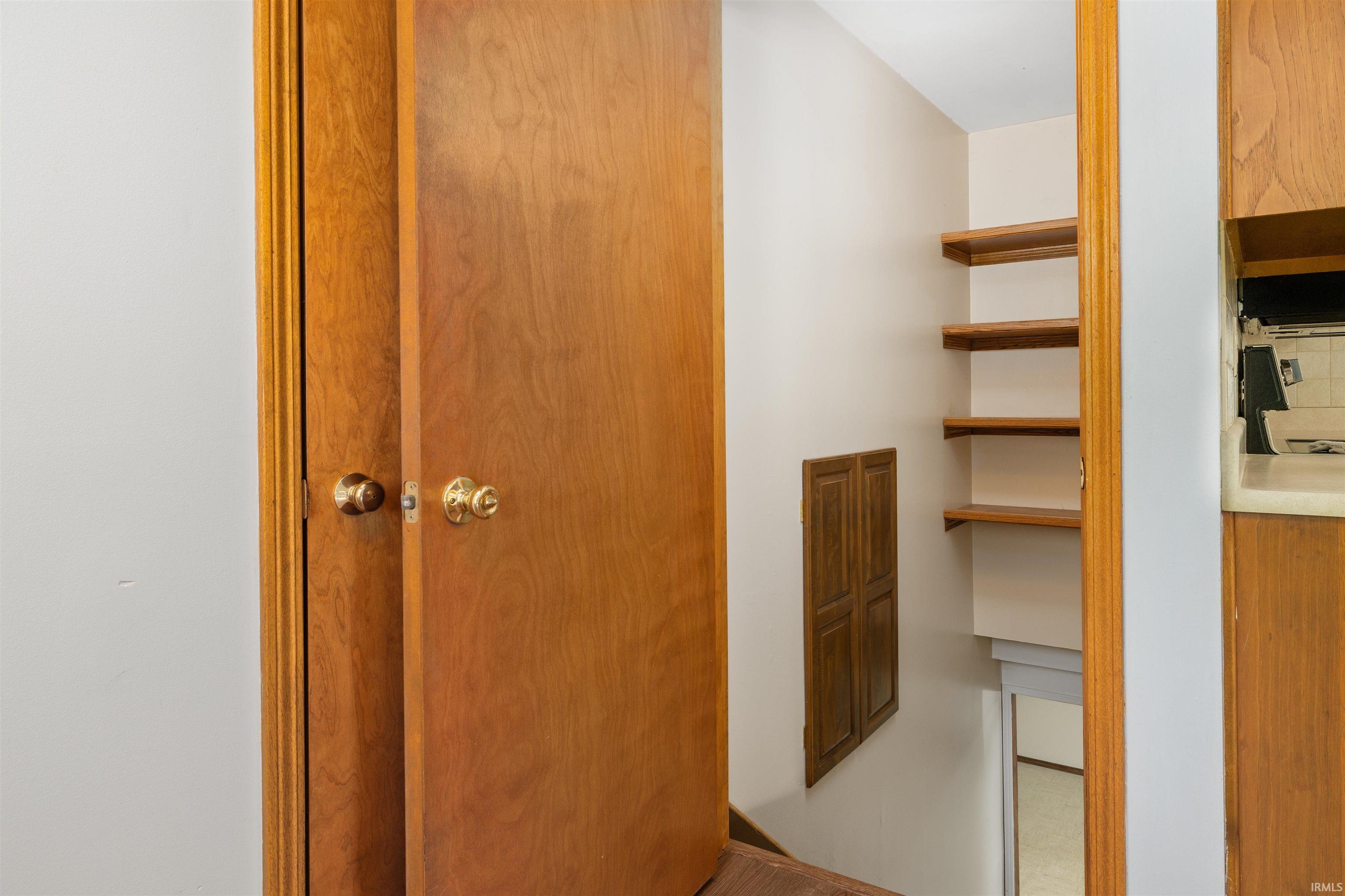 Wood-finish doors with brass hardware complimenting built-in shelving