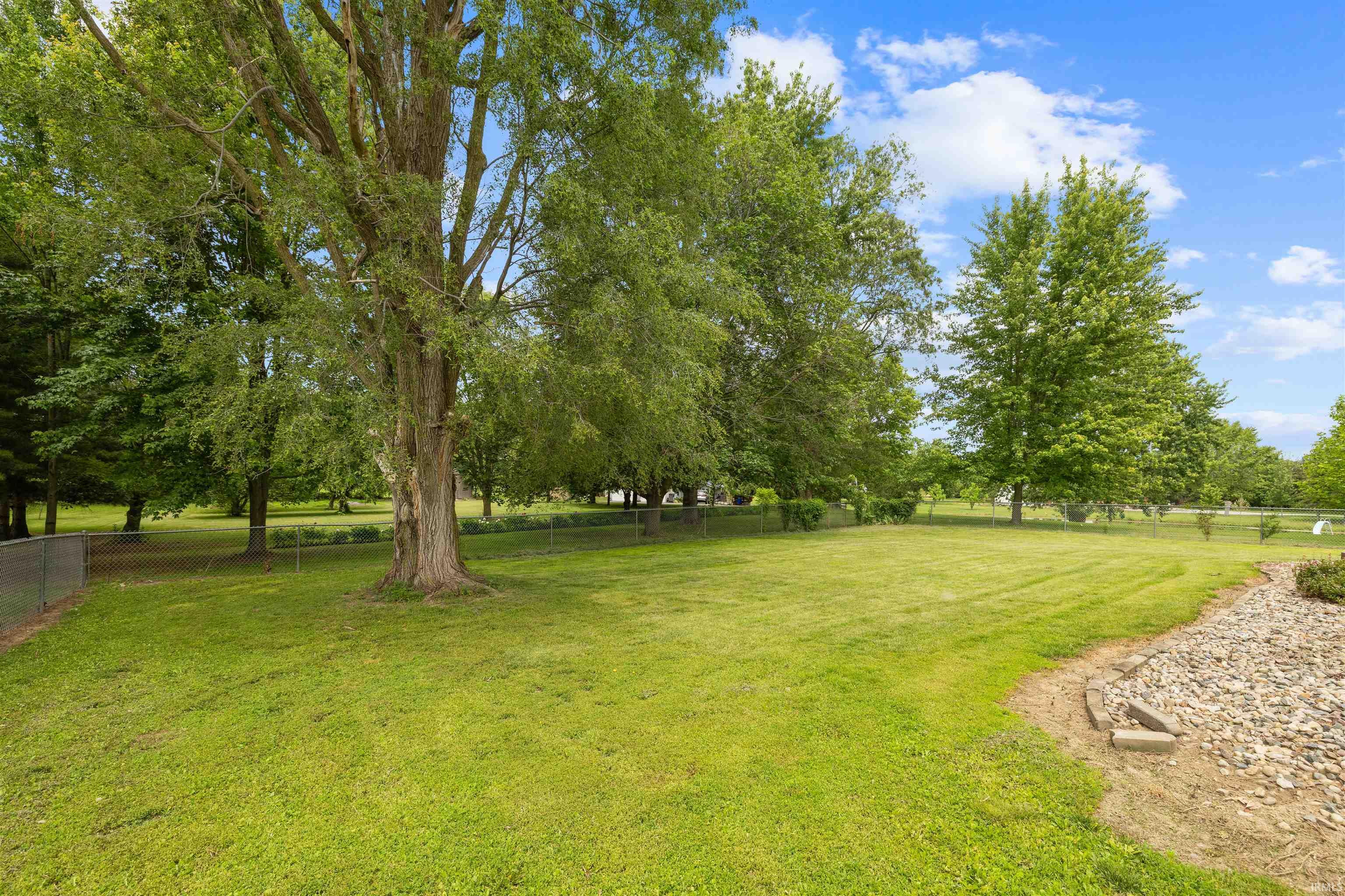 Spacious green lawn with mature trees and a rock-filled landscape bed