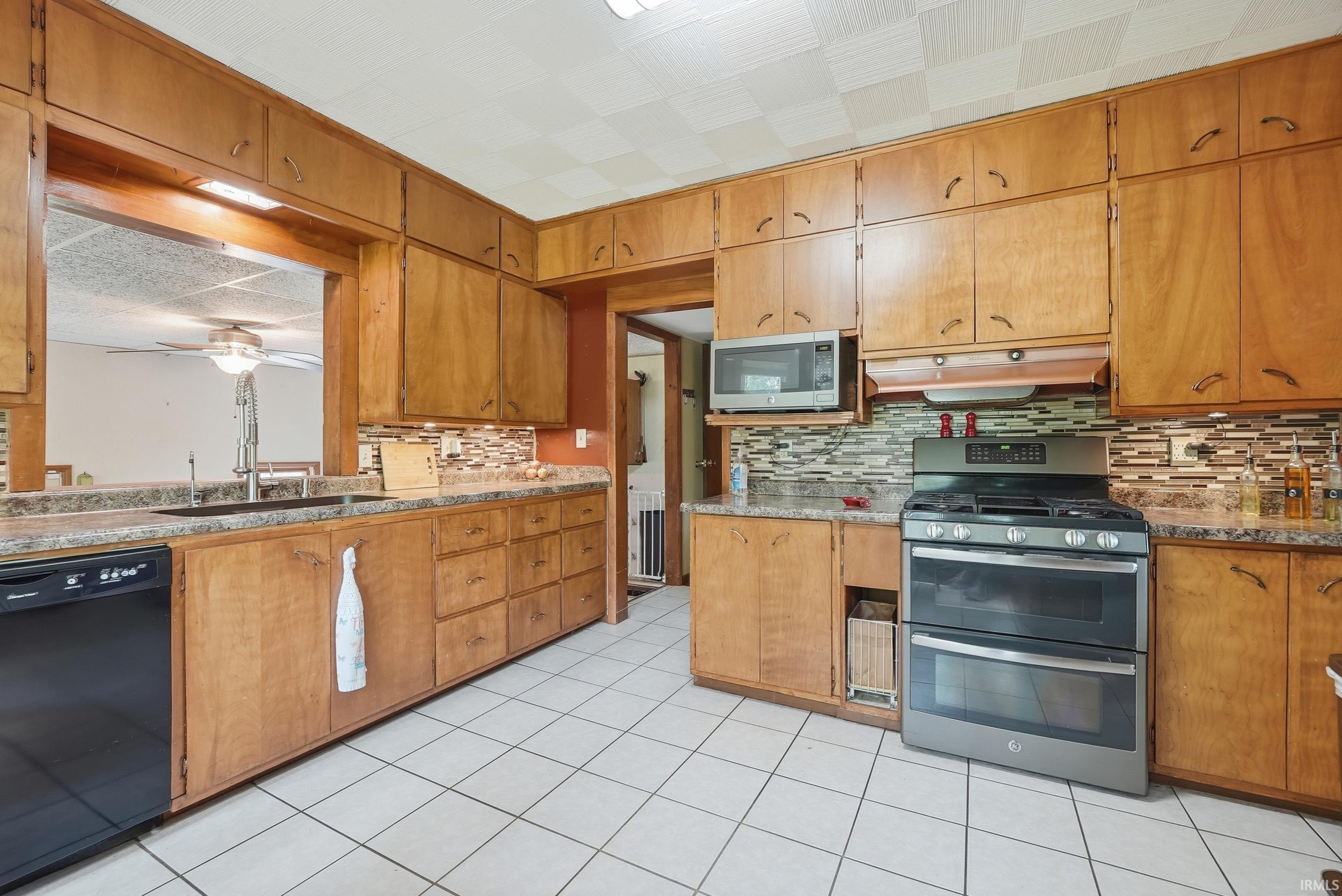 Kitchen featuring extensive wood cabinetry, stone-finish countertops, and a tiled backsplash