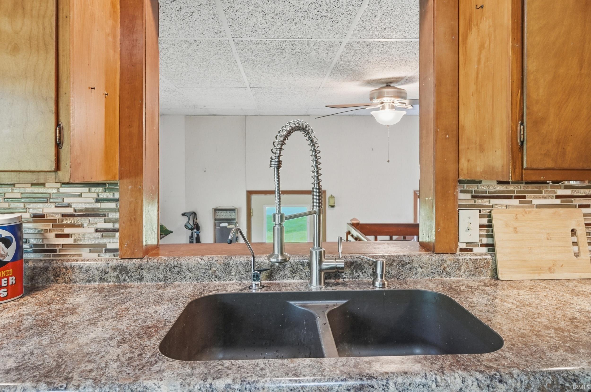 Kitchen sink featuring a gooseneck faucet, a dark-toned basin, and a speckled countertop