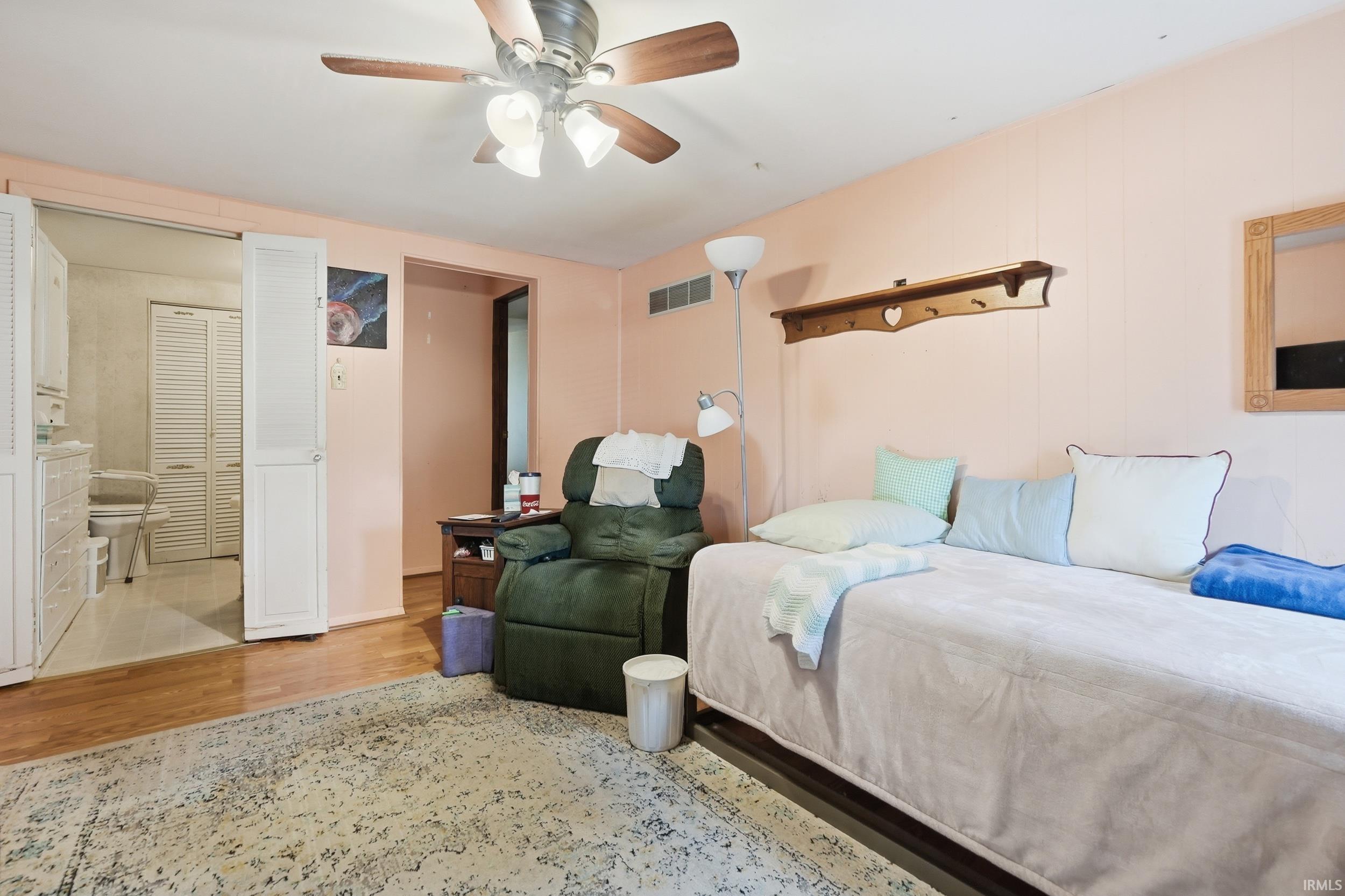 Carpeted living area with light-toned walls, wood-finish flooring, and a ceiling fan with integrated lighting