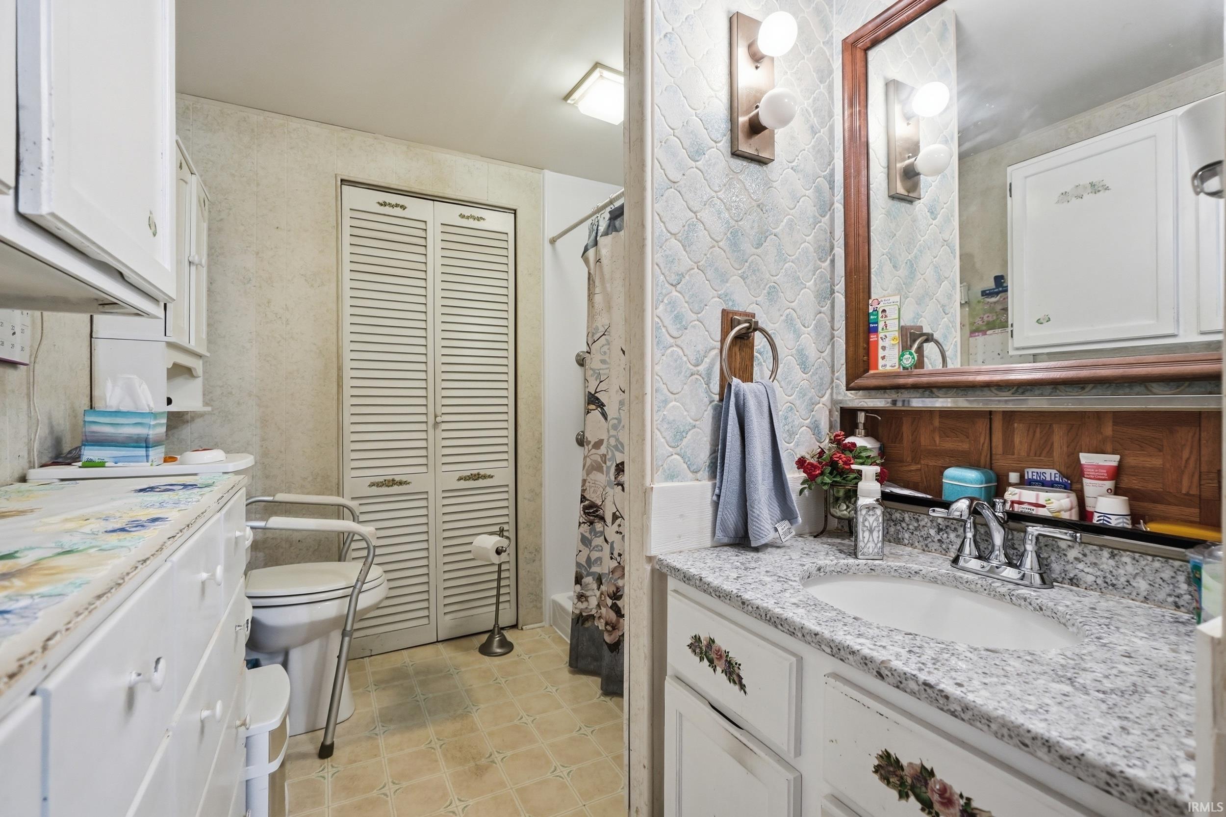 Bathroom featuring a vanity with a light speckled countertop, an undermount sink, and a framed mirror