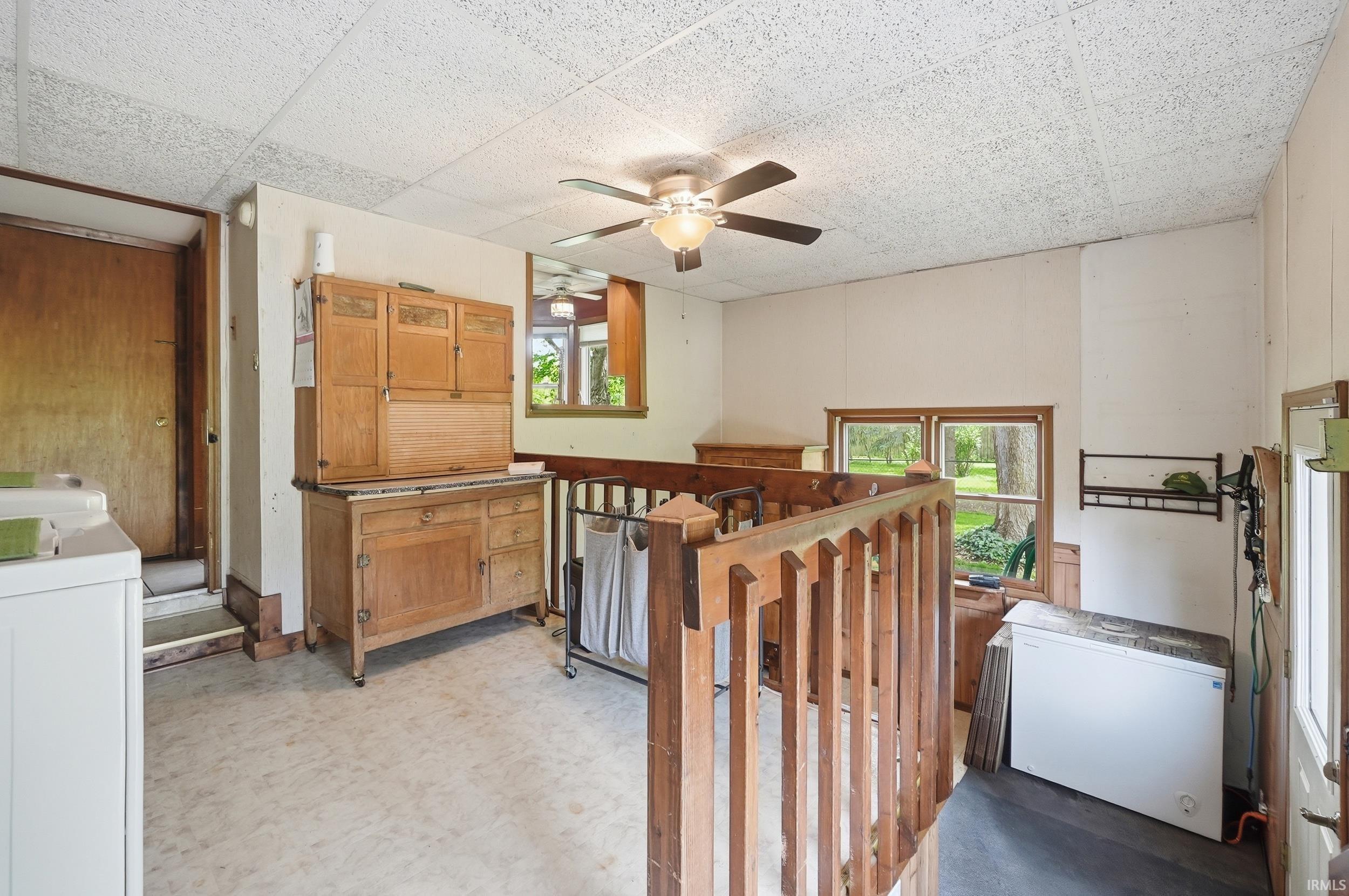 Spacious utility area featuring a ceiling fan, wood-finish flooring, windows with natural wood trim, and a built-in wood railing
