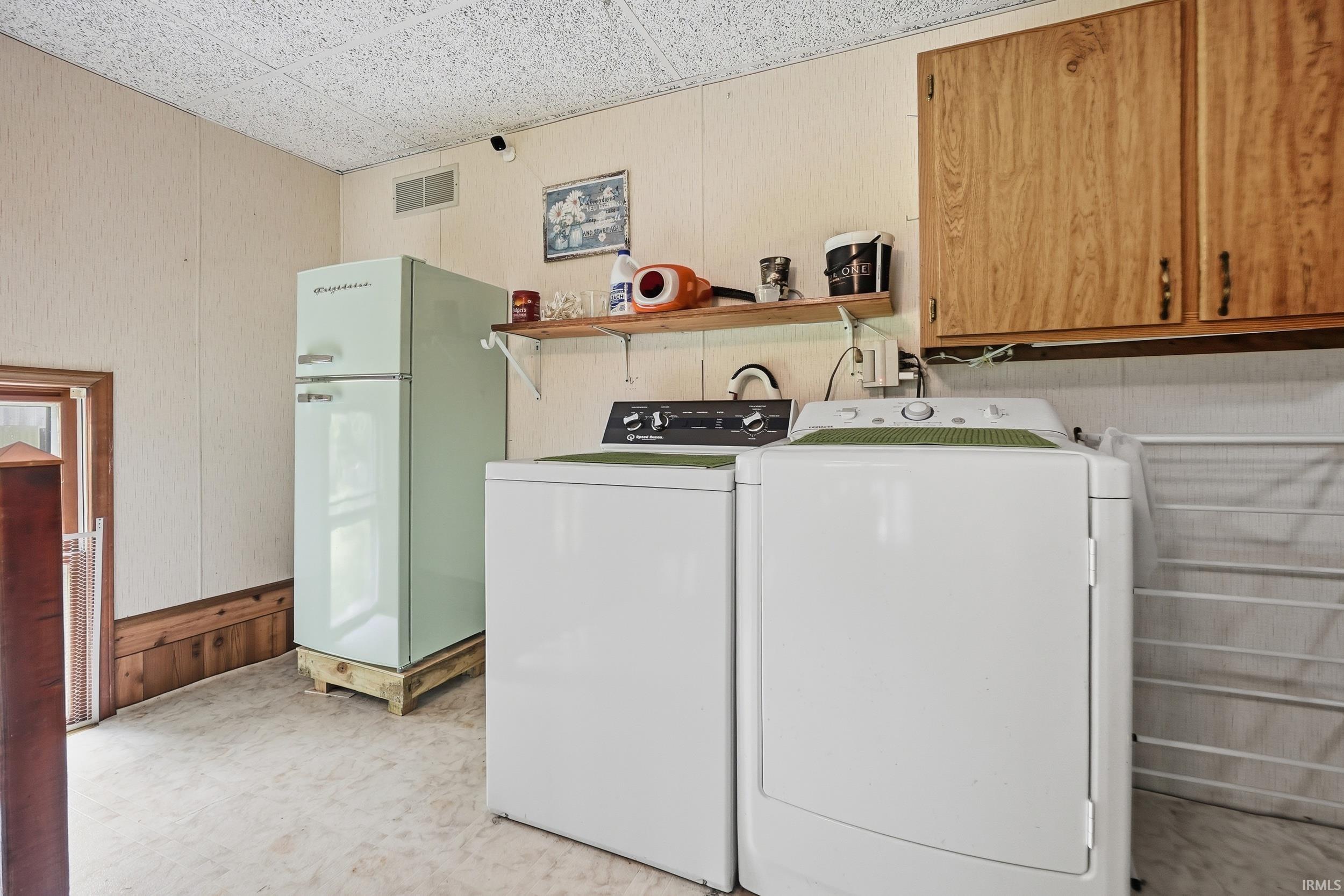 Utility area featuring a top-load washing machine, a front-load dryer, and a vintage-style refrigerator