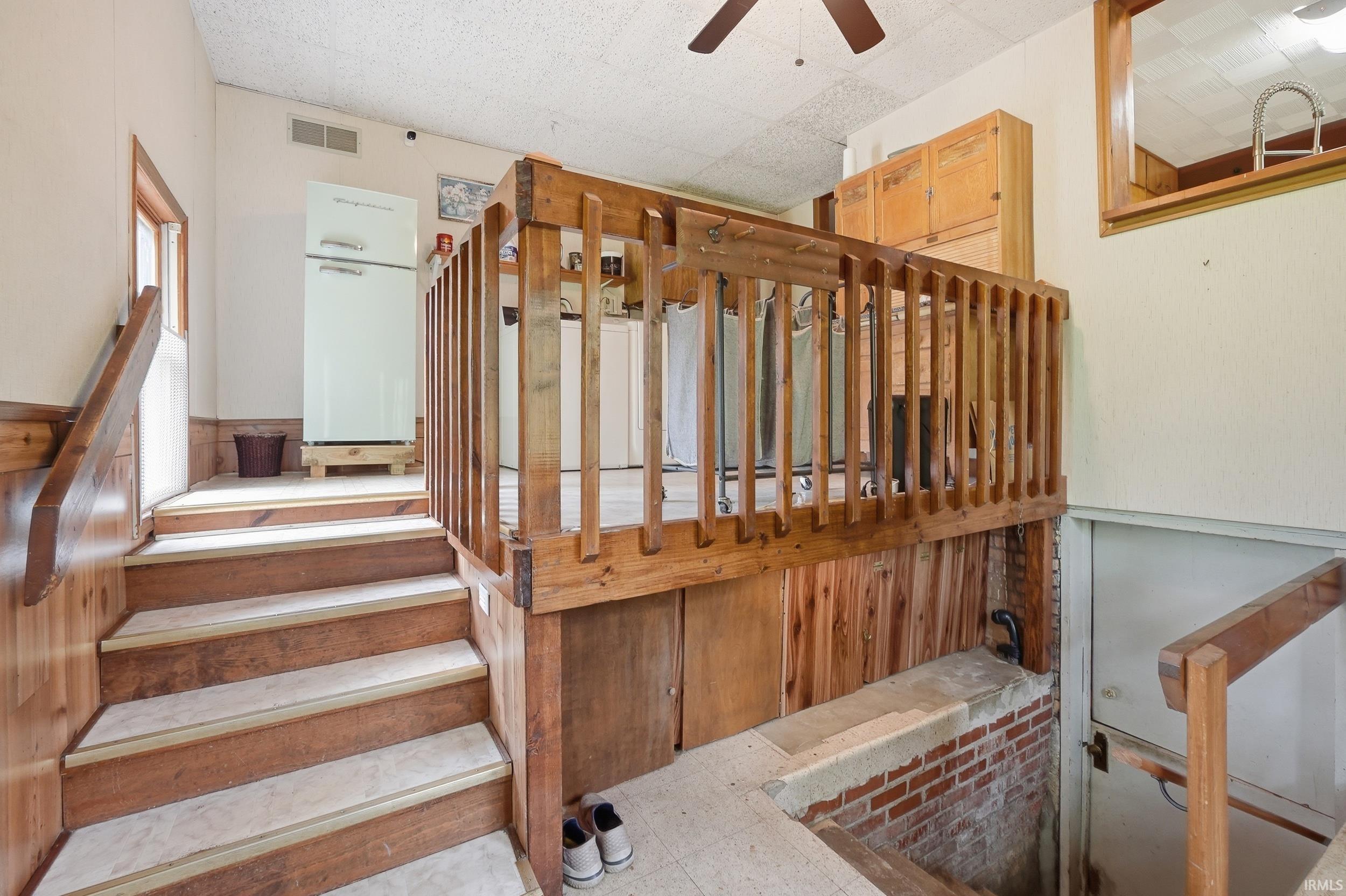 Wood-finish flooring and paneling on staircase leading to a landing with a built-in wooden half-wall railing