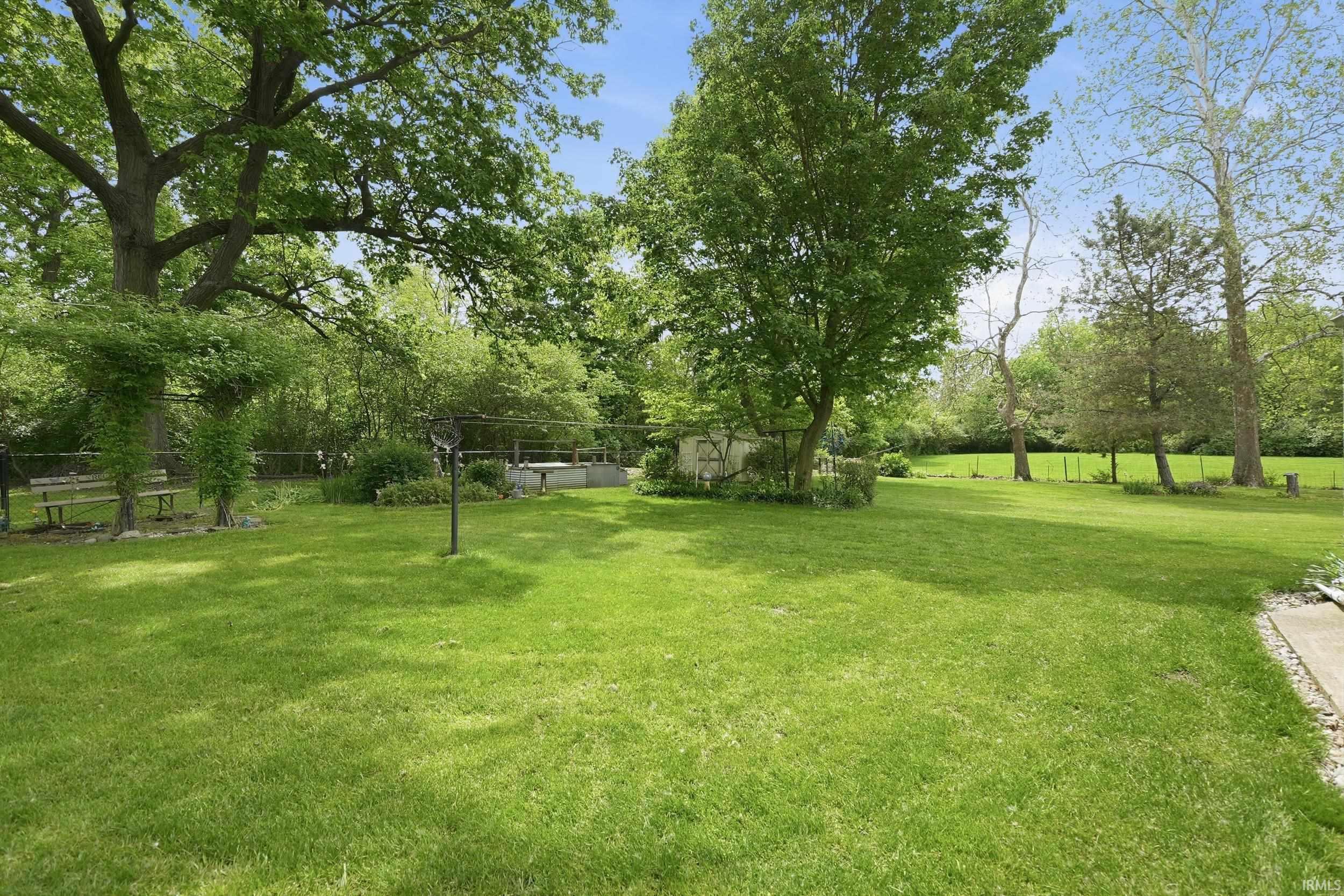 Expansive green lawn with mature trees and a subtle partial fence line