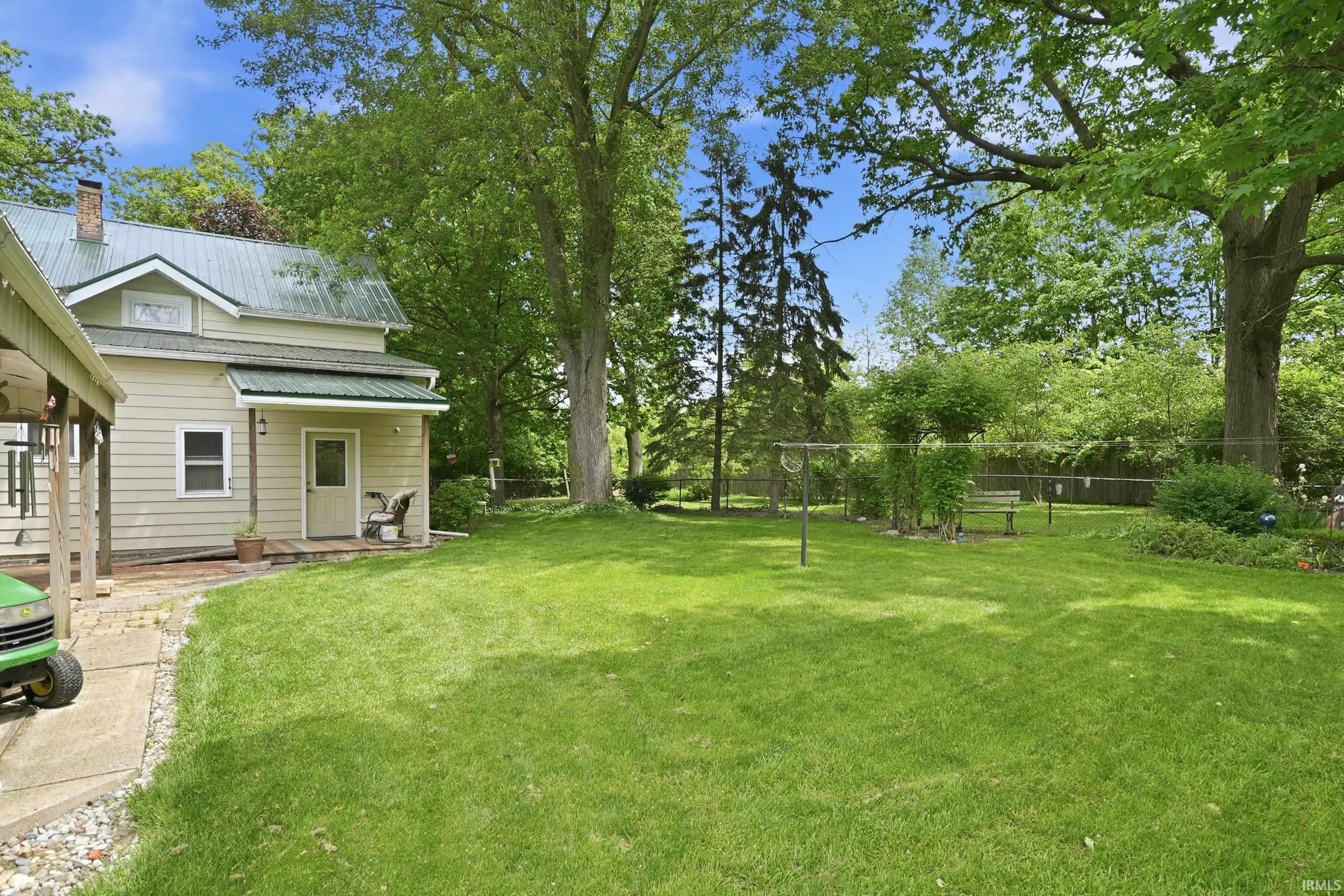 Expansive rear yard featuring a manicured lawn, mature trees, and privacy fencing