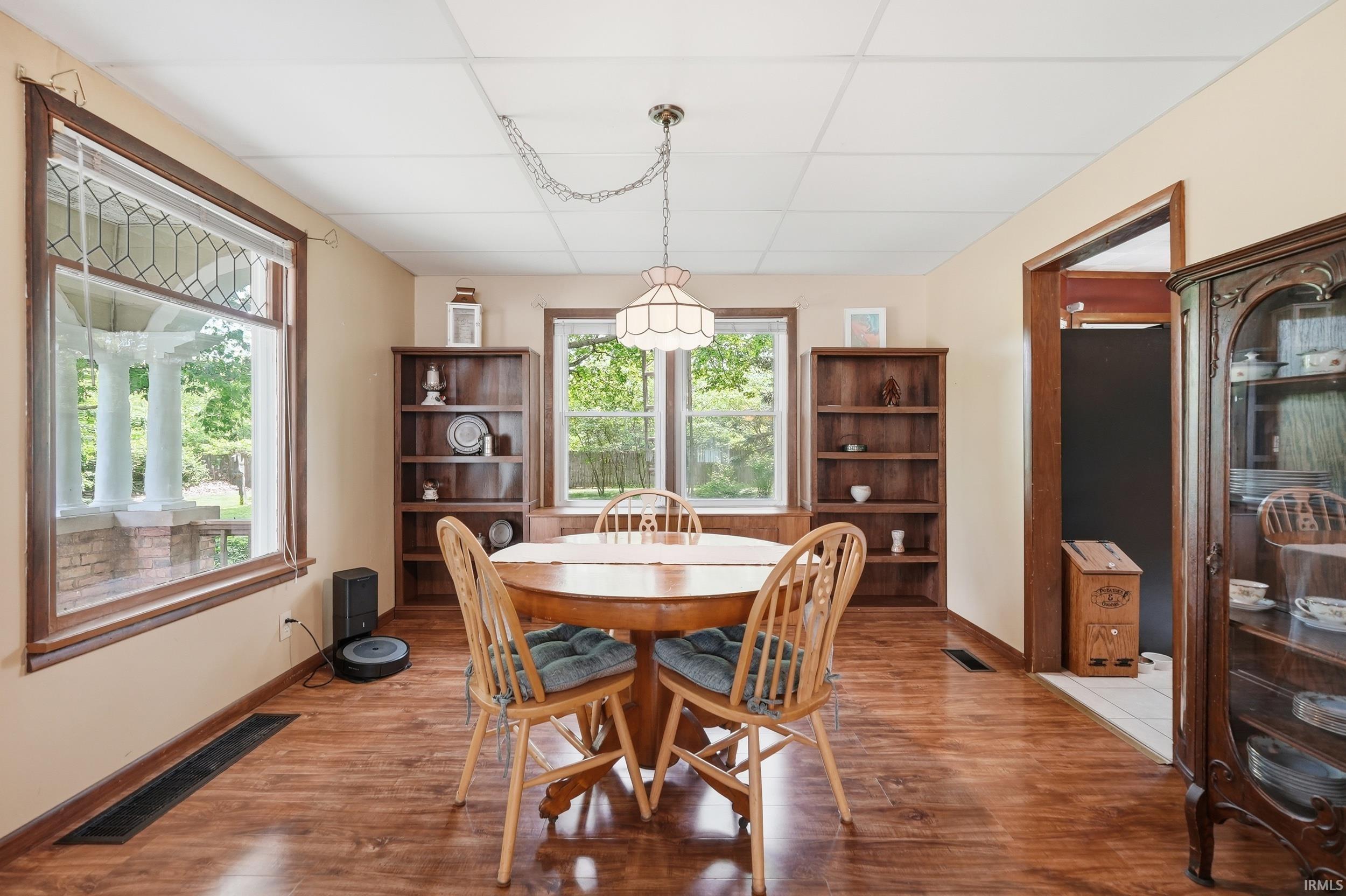 Spacious room featuring wood-finish flooring, two large windows, and built-in shelving units