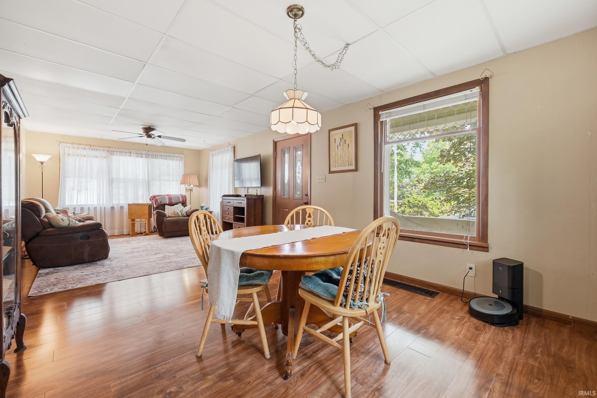 Open-concept living area featuring wood-finish flooring, a ceiling fan, and multiple windows with natural light