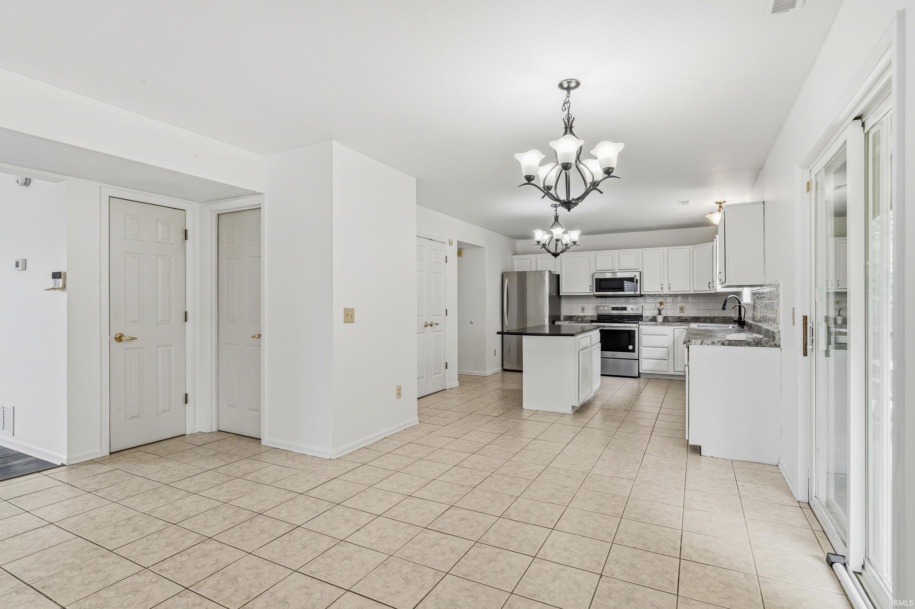 Open-concept kitchen and living area featuring neutral tile flooring