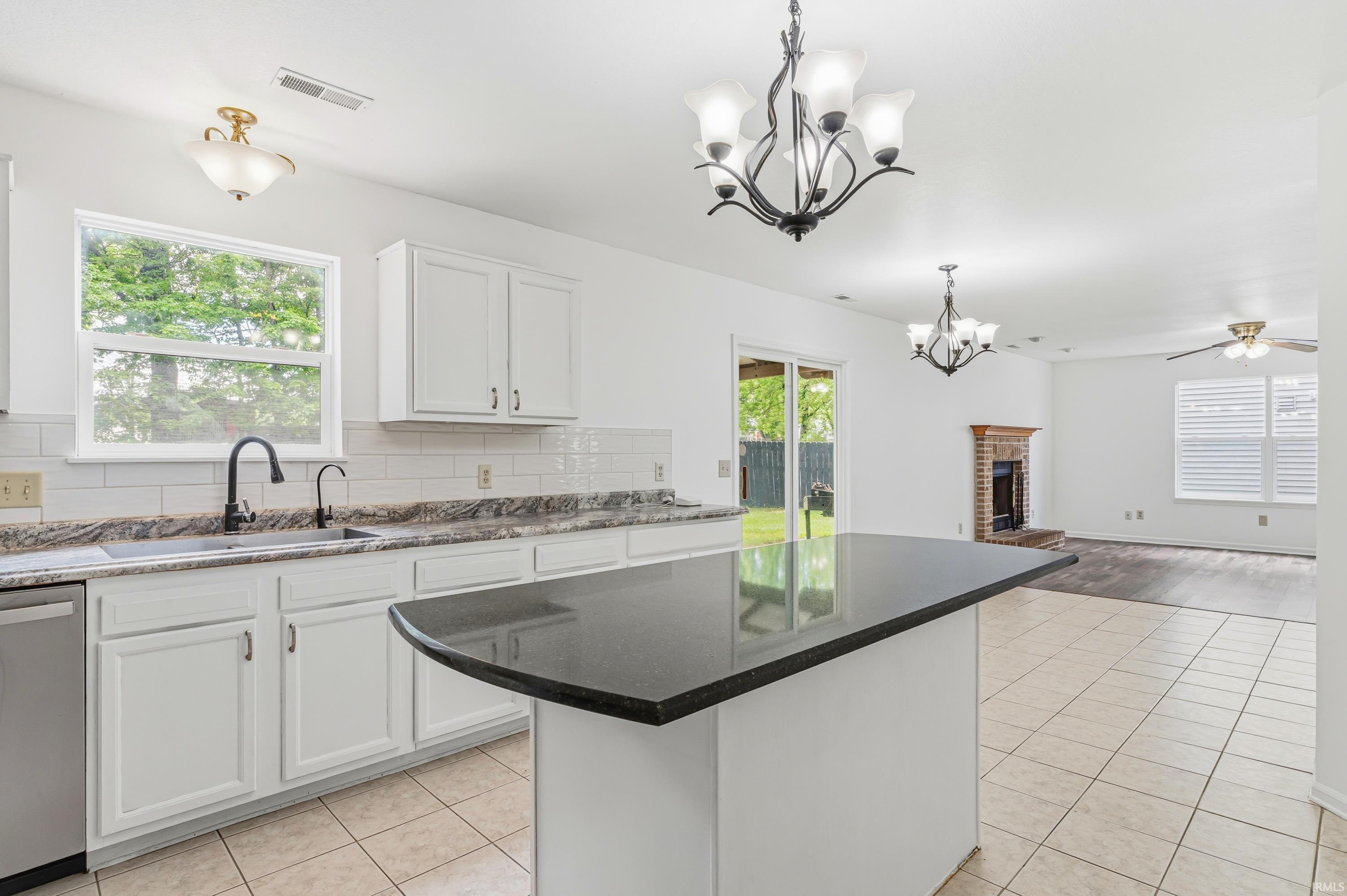 Kitchen featuring white cabinetry, dark stone countertops, stainless steel appliances, a center island with a dark stone top, and tile flooring