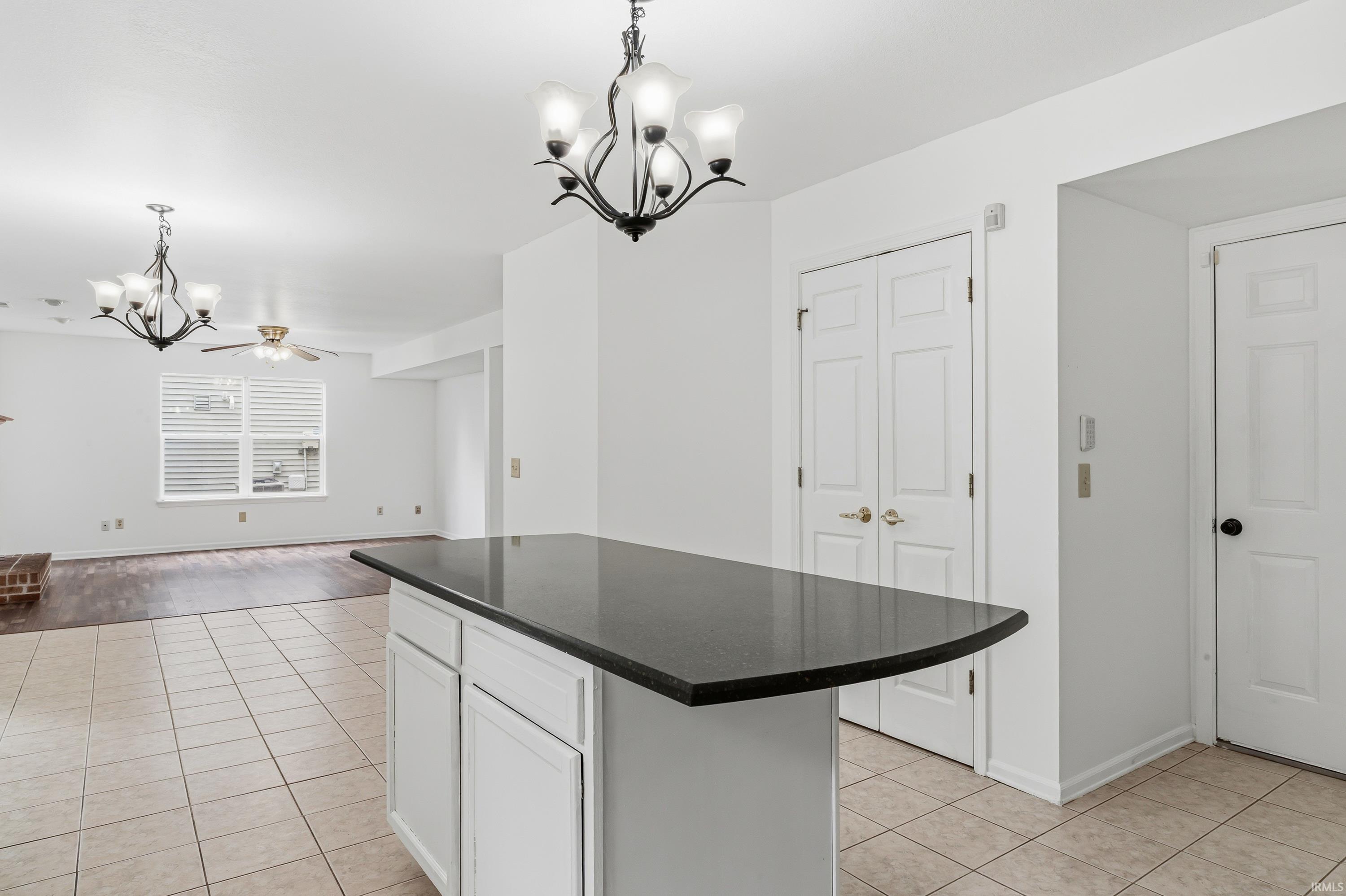 Kitchen island with a dark countertop and white cabinetry, complemented by light-toned square tile flooring