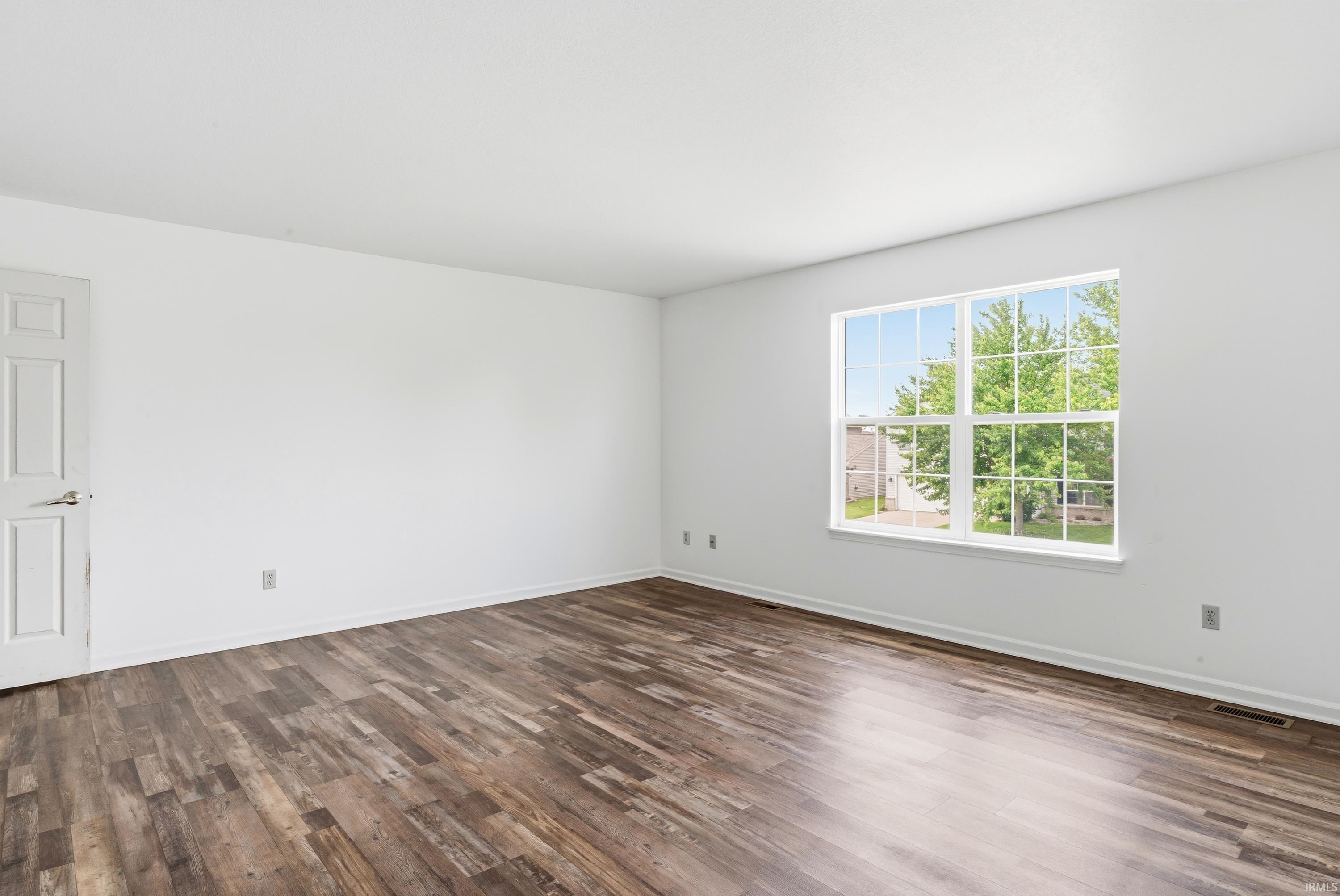 Bright interior space featuring wood-finish flooring, white walls, and a multi-pane window