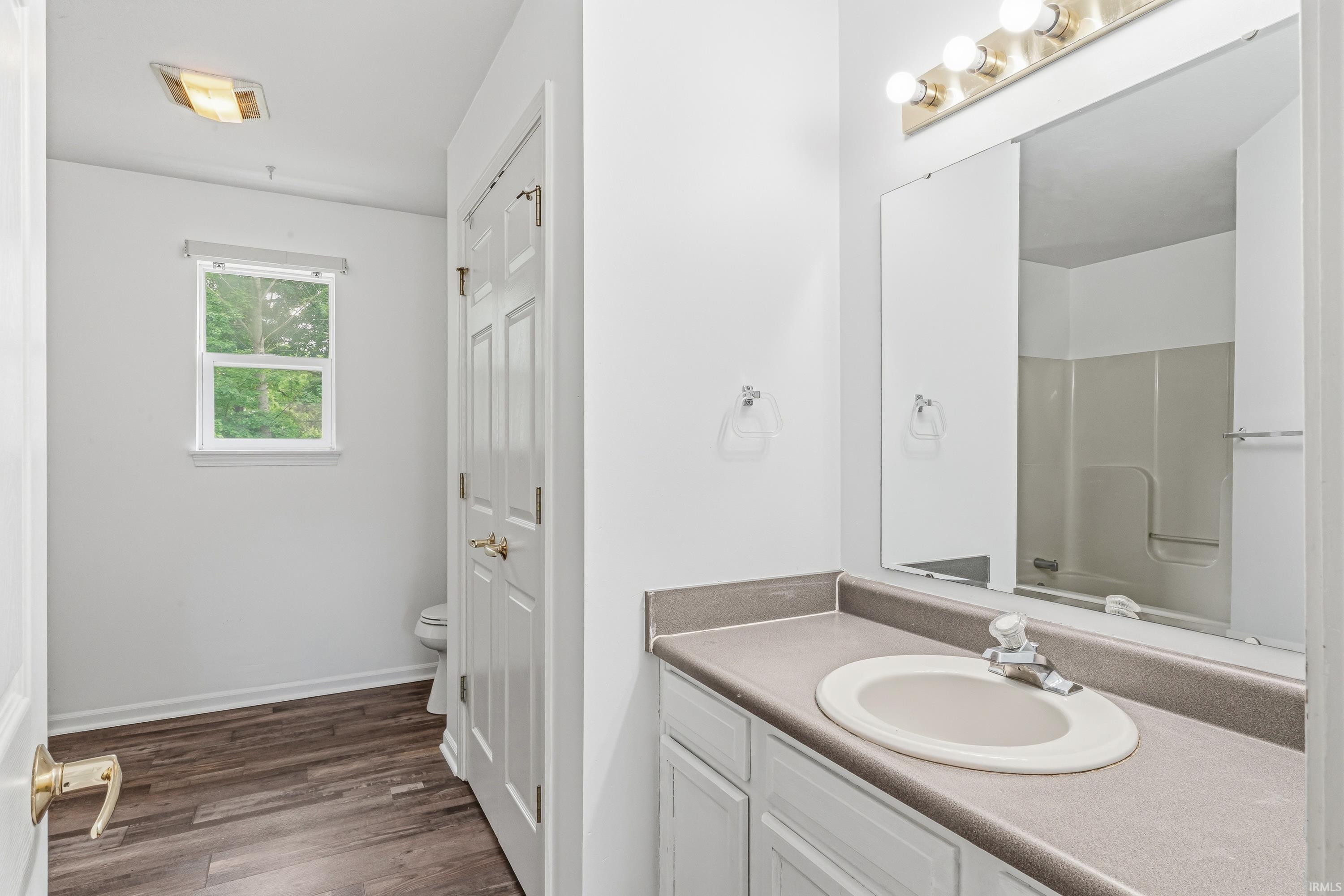 Bathroom vanity featuring a light gray countertop with an integrated sink, polished chrome faucet, and white cabinetry