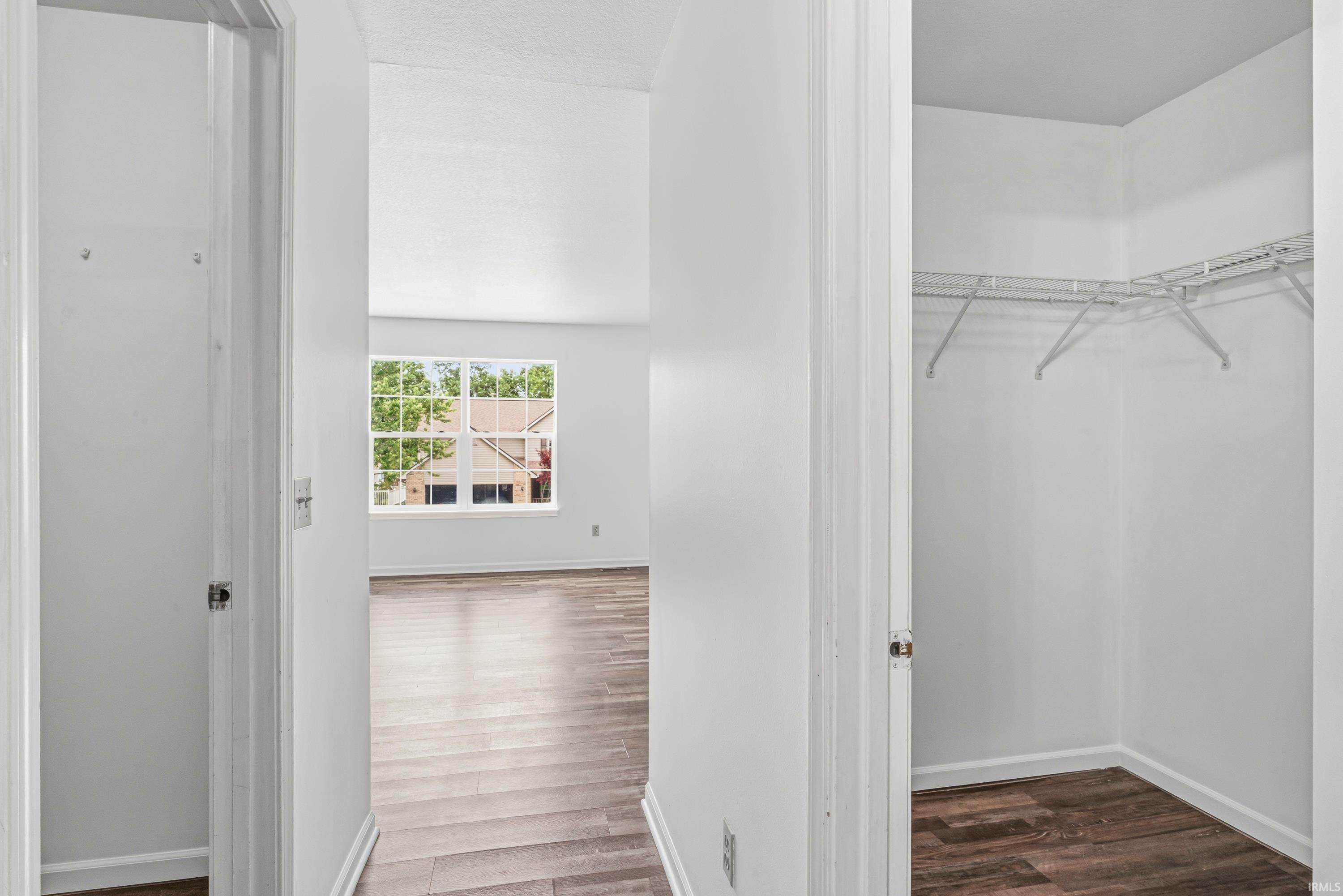 Bedroom featuring wood-finish flooring, a vaulted ceiling, and a large window with white trim