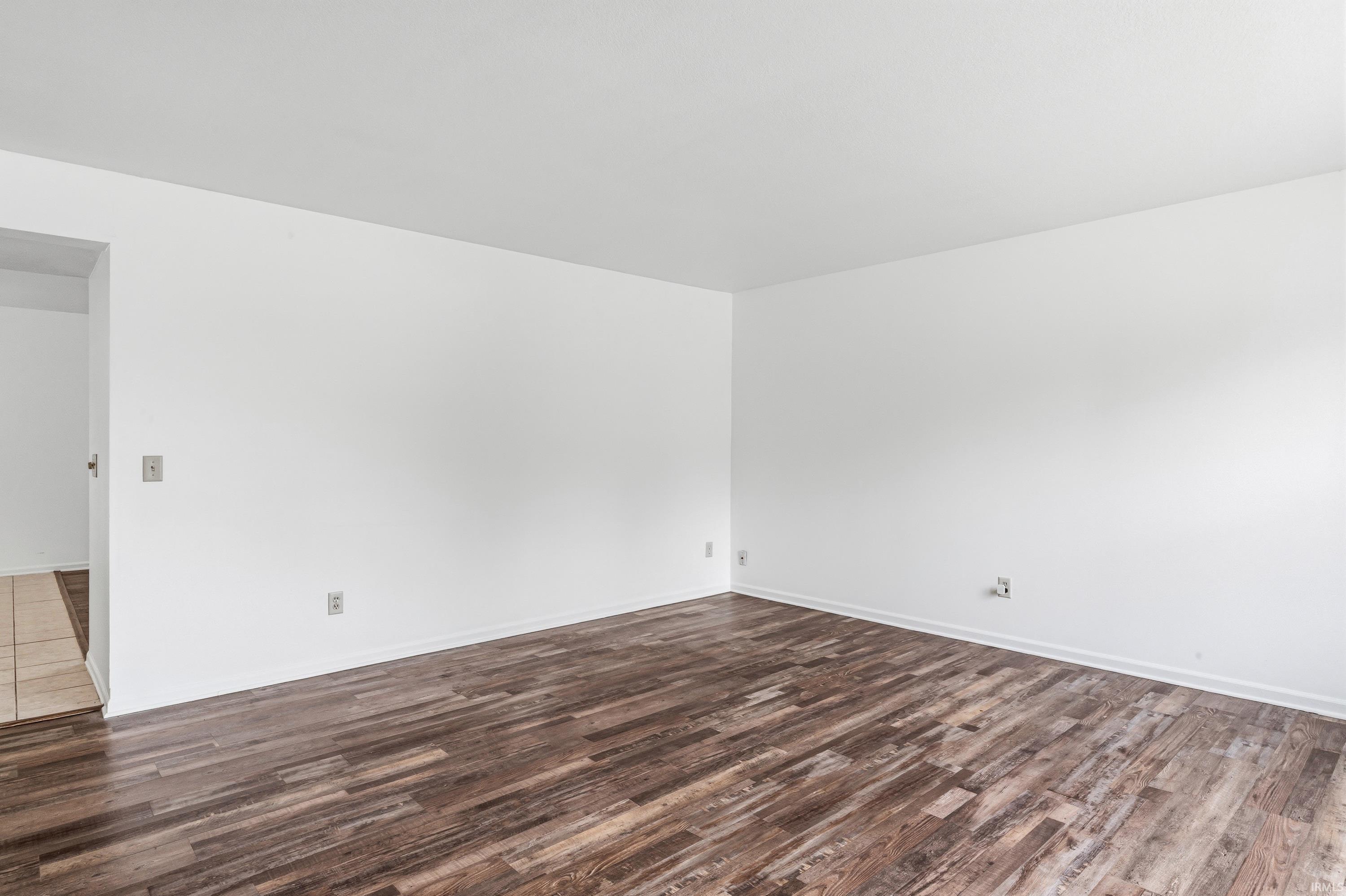 Spacious room featuring wood-finish flooring and neutral white walls
