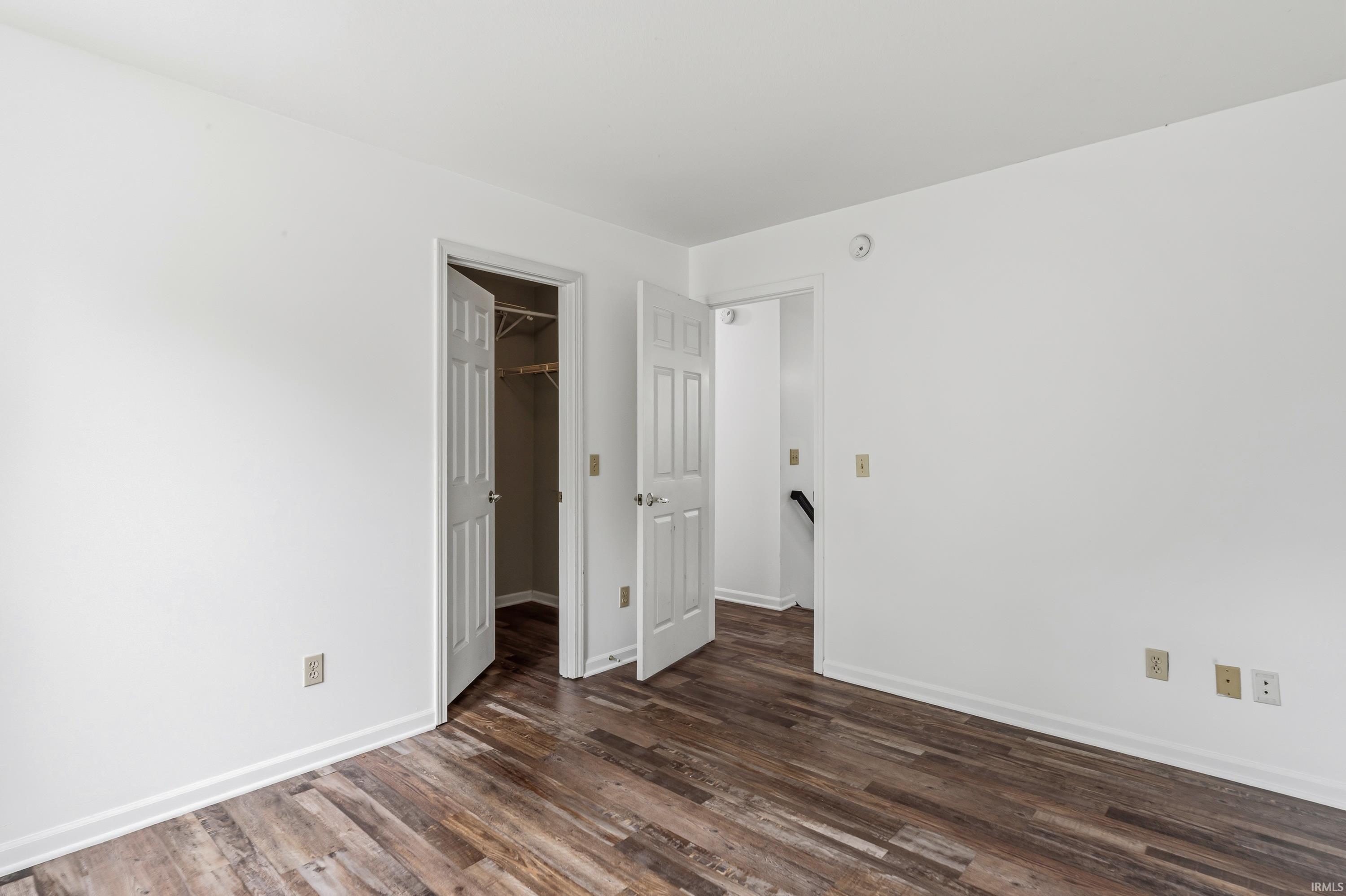 Interior room featuring wood-finish flooring, white walls, and white baseboards