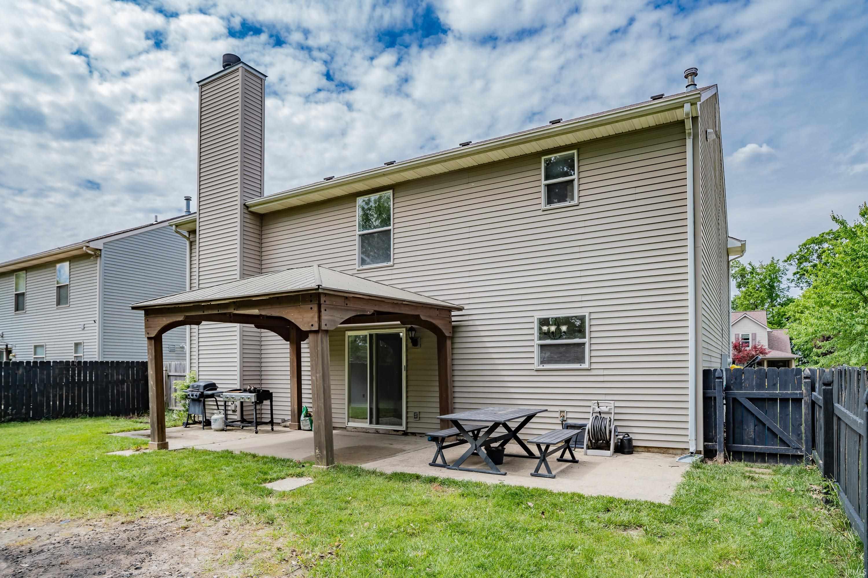 Rear exterior featuring a patio with a pergola, sliding glass door access, an extended chimney, and horizontal siding