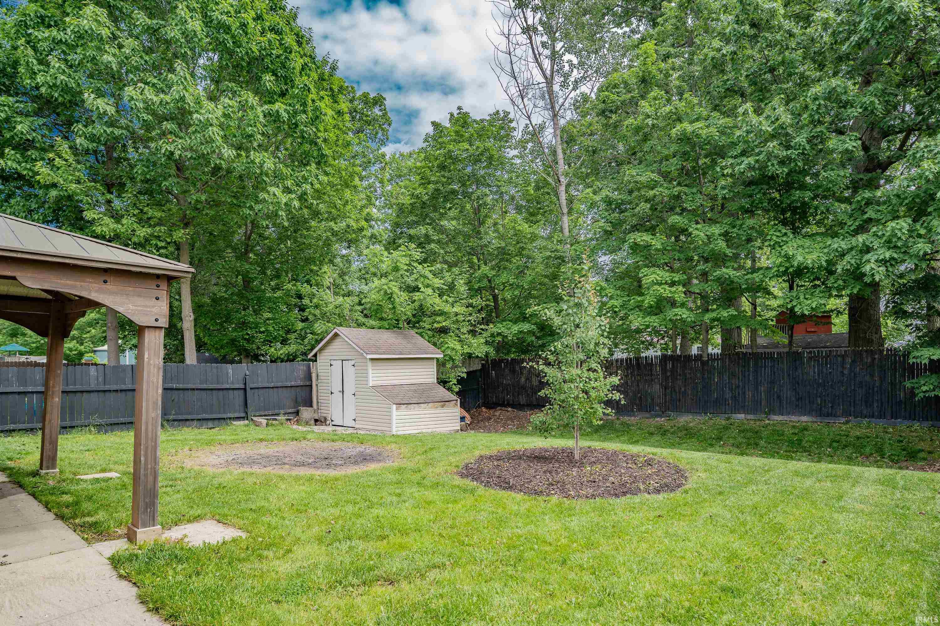 Expansive backyard featuring a lush lawn, mature trees, and privacy fencing