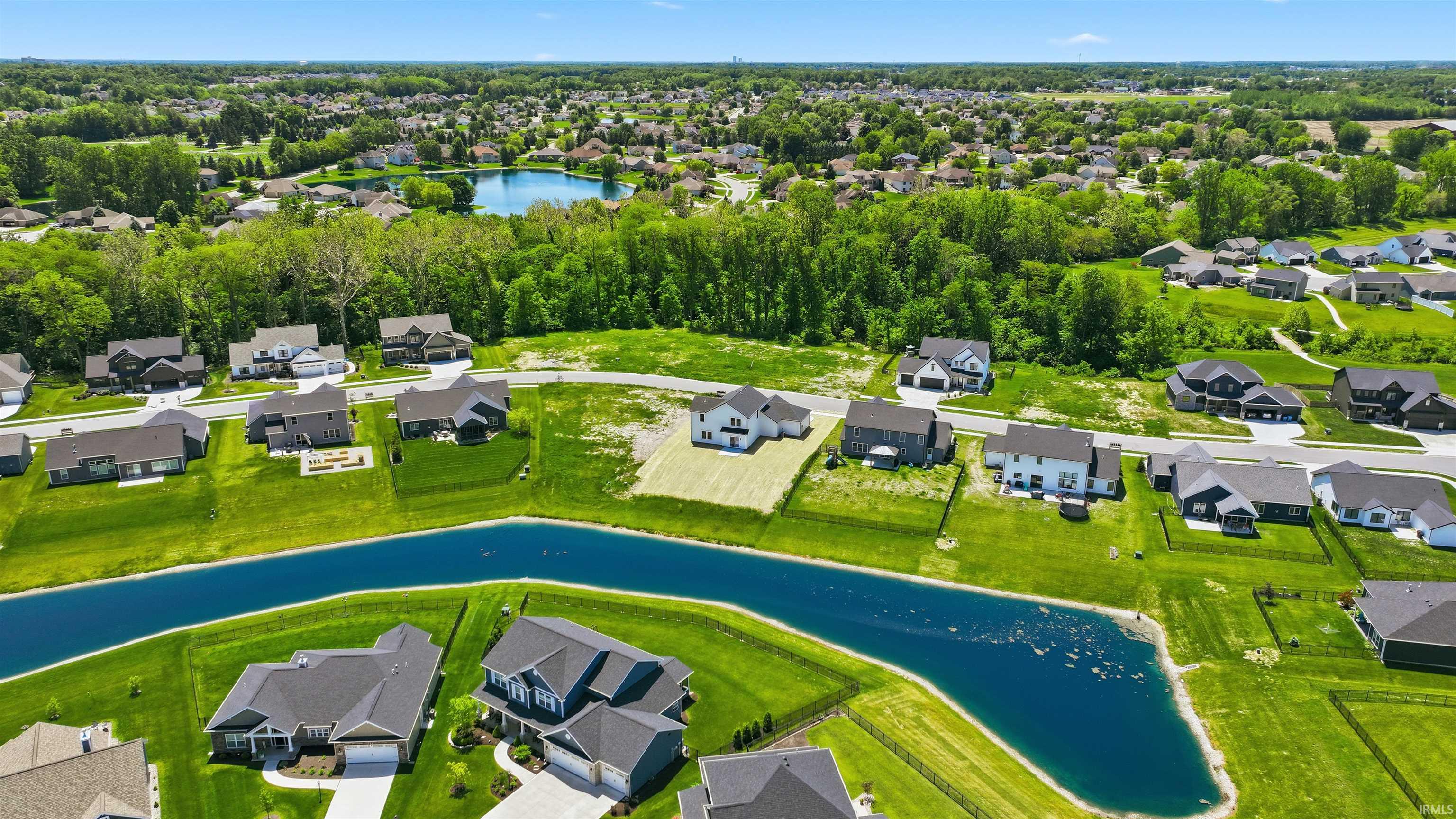 Aerial perspective of a developed residential community featuring a prominent water amenity