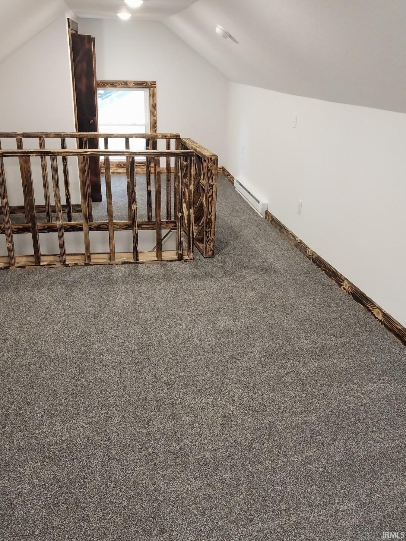 Carpeted loft area featuring a unique wooden railing and trim details