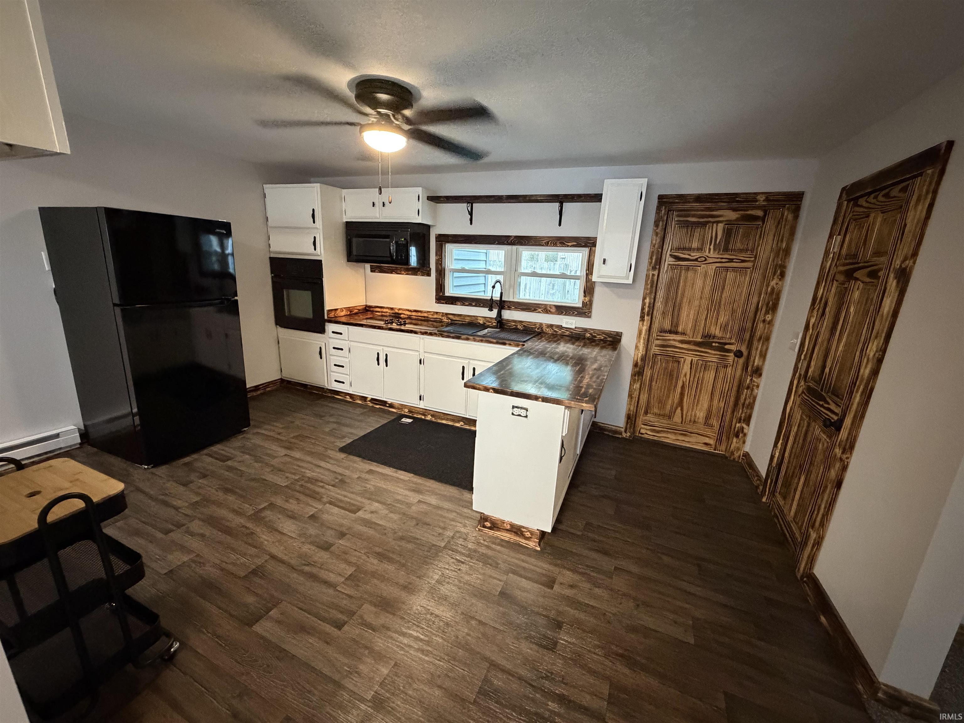 Kitchen featuring wood-finish flooring, white cabinetry, and dark countertops