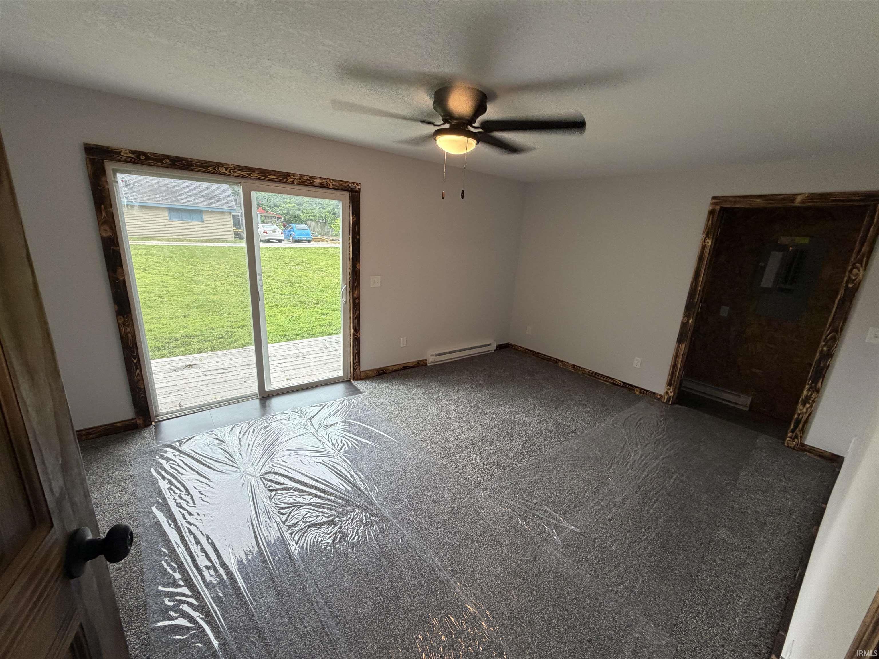 Room featuring new gray carpeting, white walls, and wood-finish trim