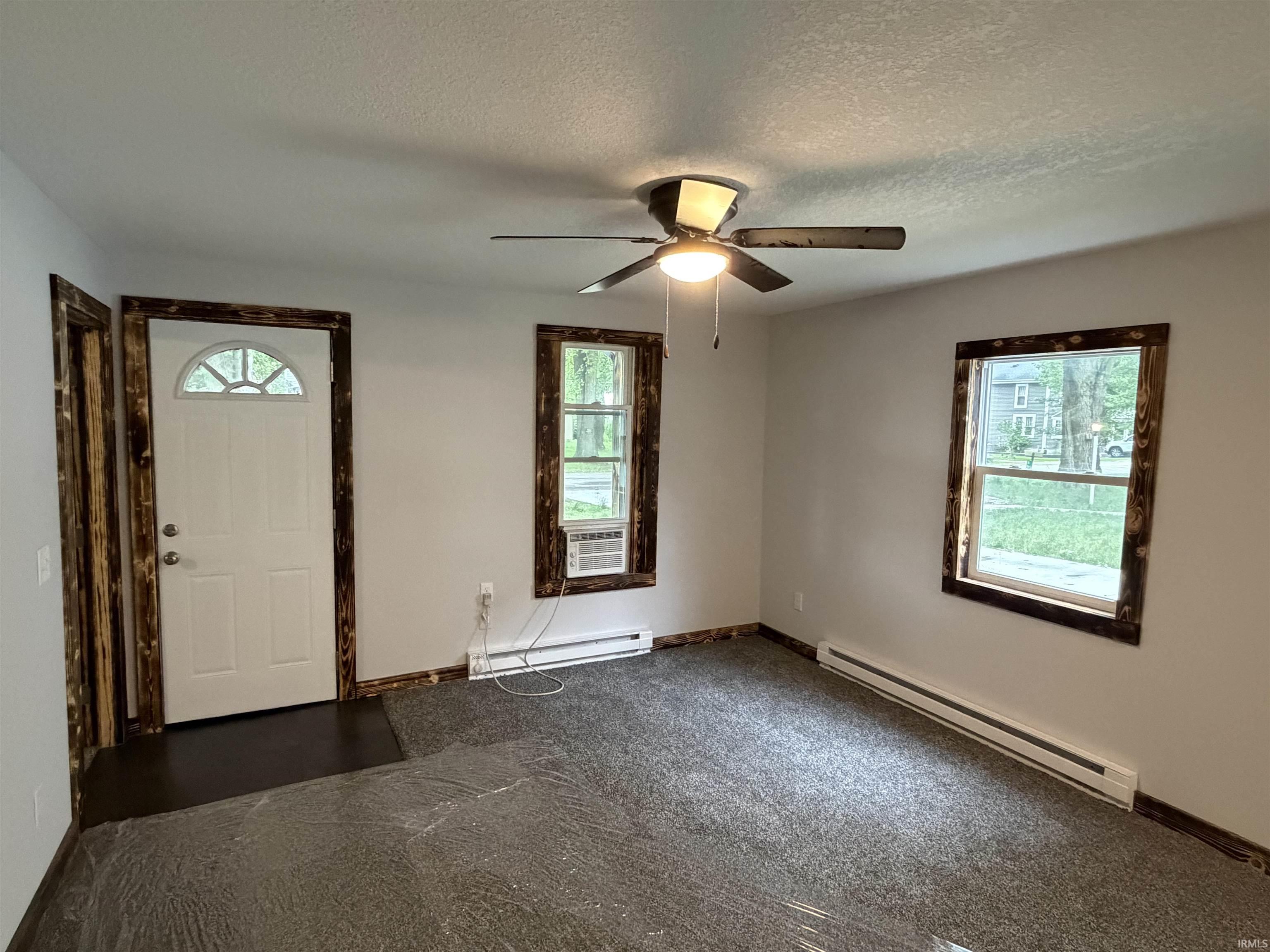 Interior room featuring light gray wall paint and dark wood-finish trim around windows and doorway