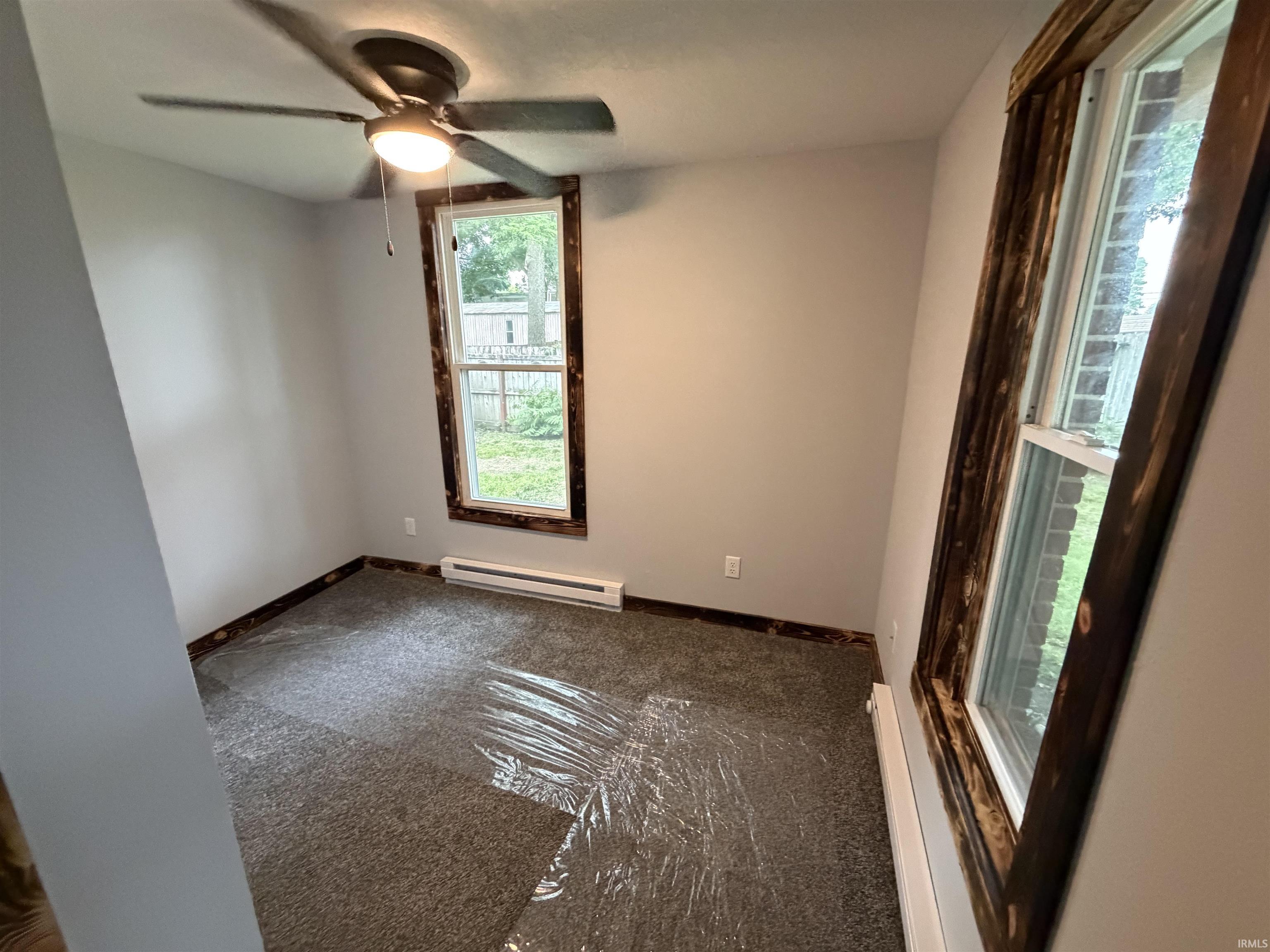 Interior room featuring light gray walls, dark wood-tone window trim, and a ceiling fan with integrated lighting