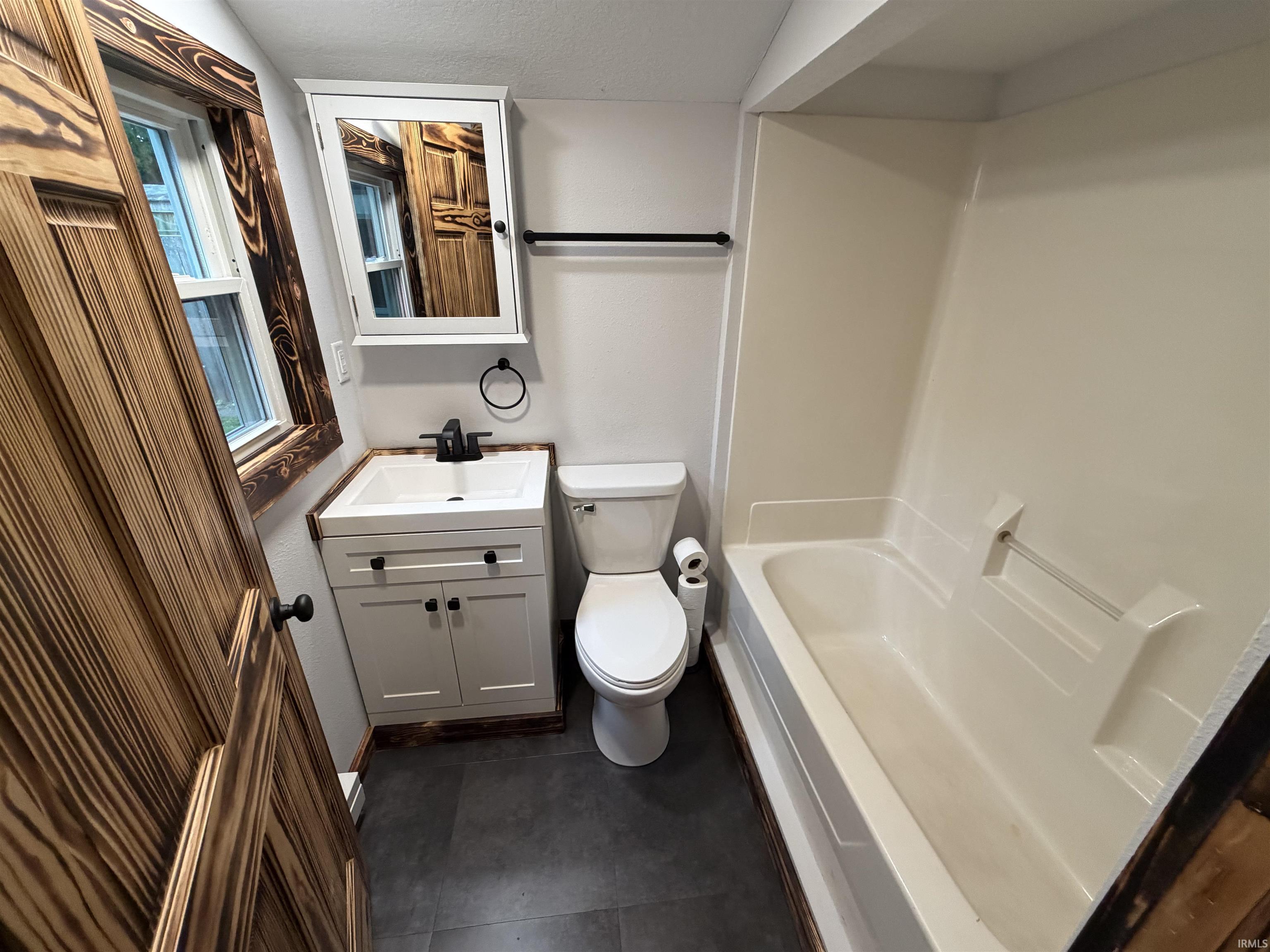 Bathroom featuring a white vanity with integrated sink, black fixtures, and a medicine cabinet
