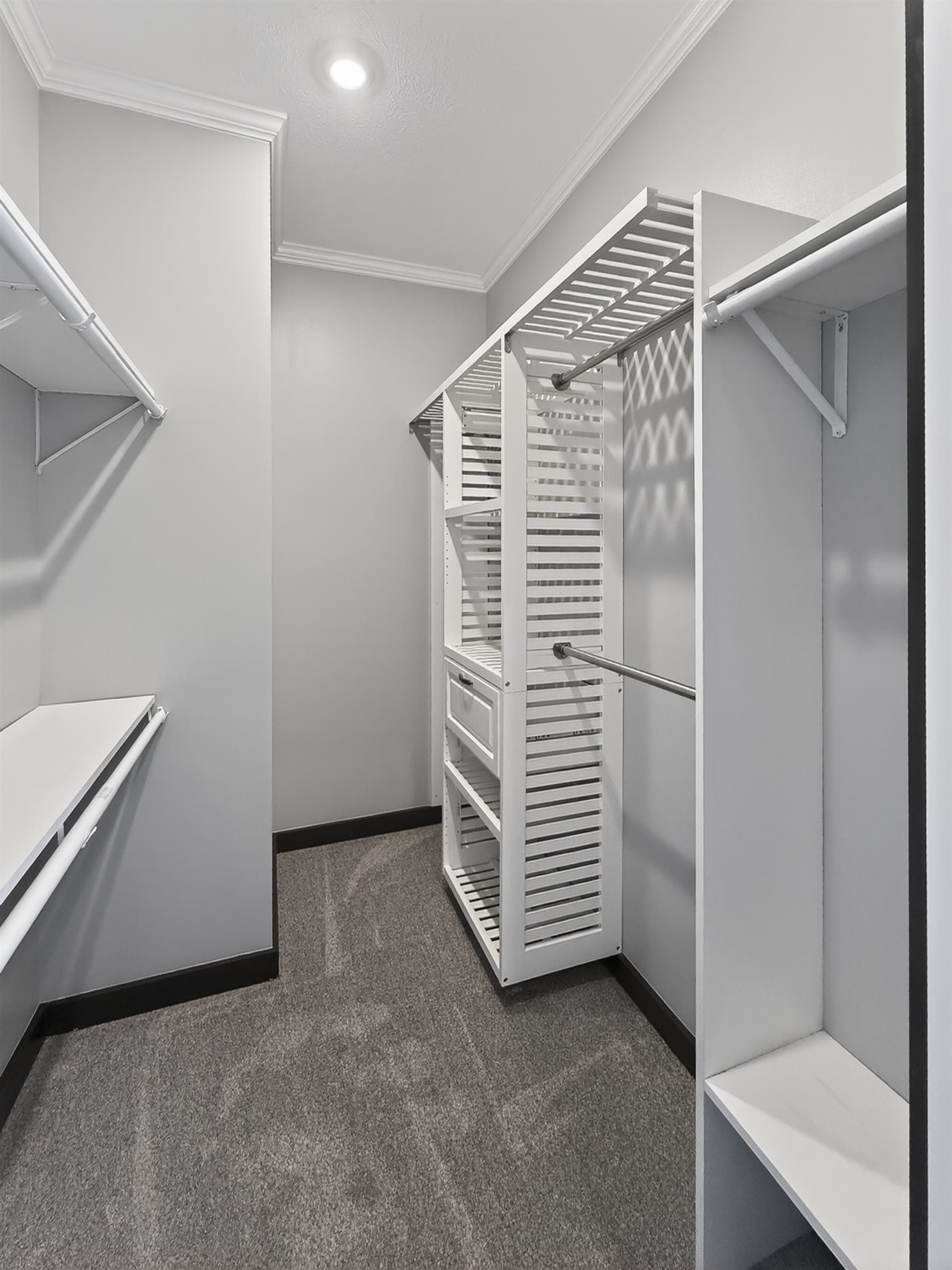 Custom closet system featuring multiple shelves, hanging rods, and an integrated drawer unit