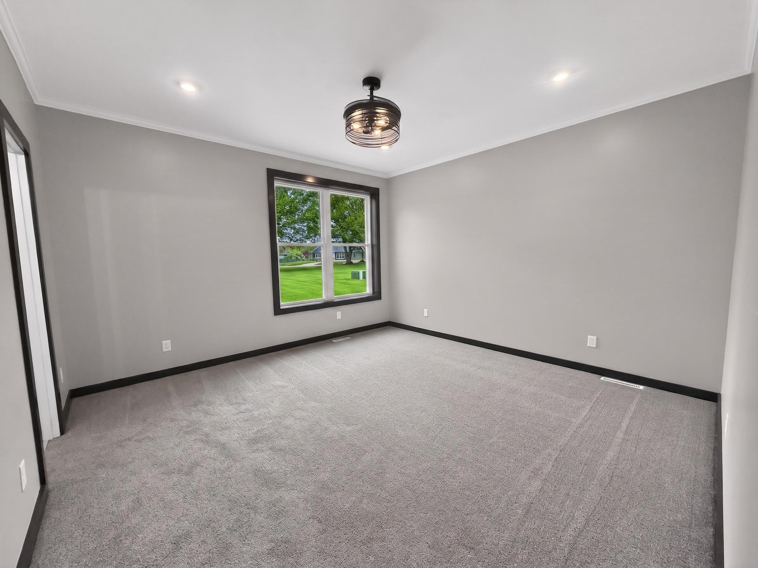 Spacious room featuring neutral carpeting, a large window with dark trim, recessed lighting, and a modern ceiling fixture