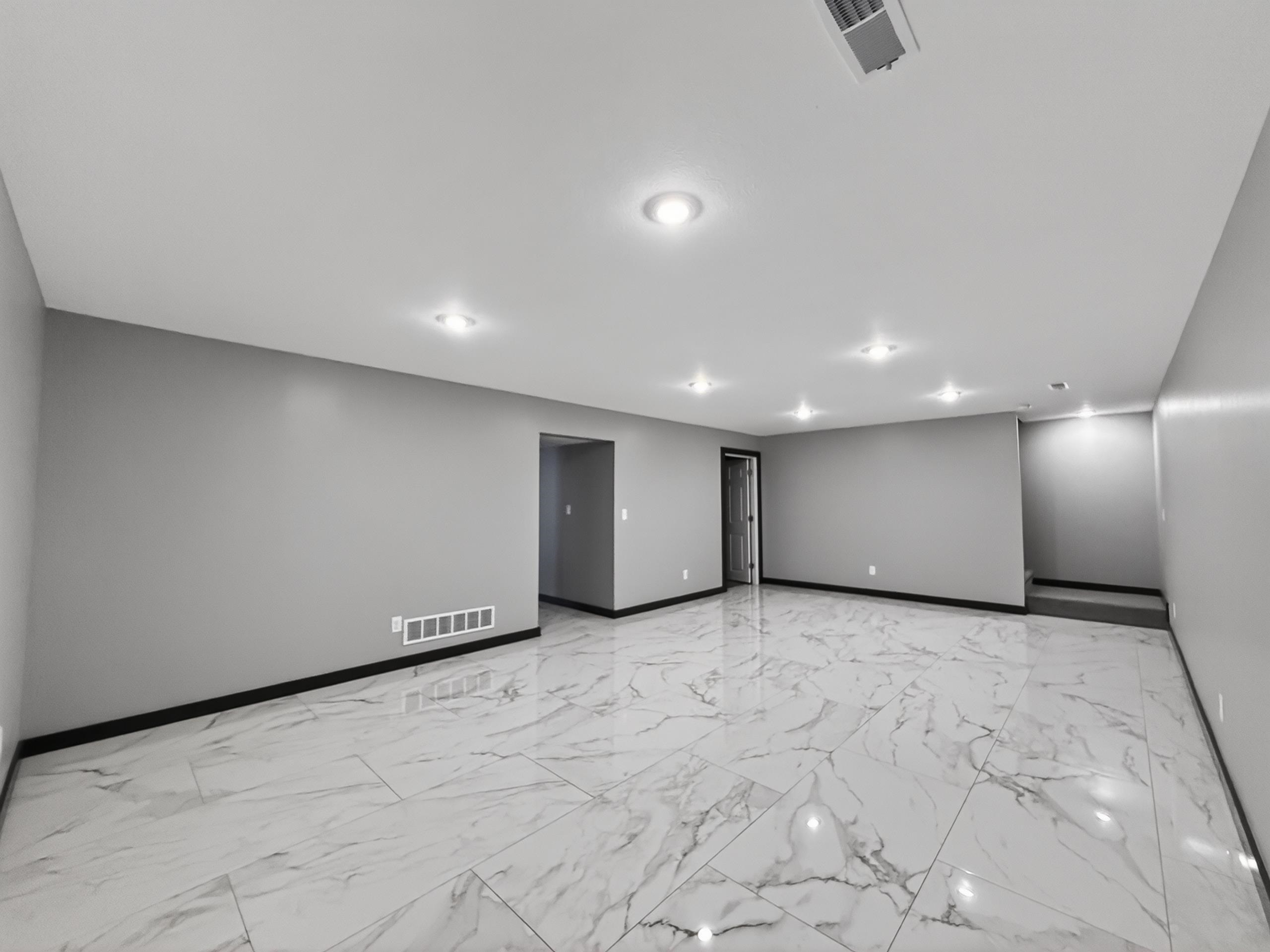 Spacious room featuring large format tile flooring, recessed ceiling lighting, light gray painted walls, and dark trim