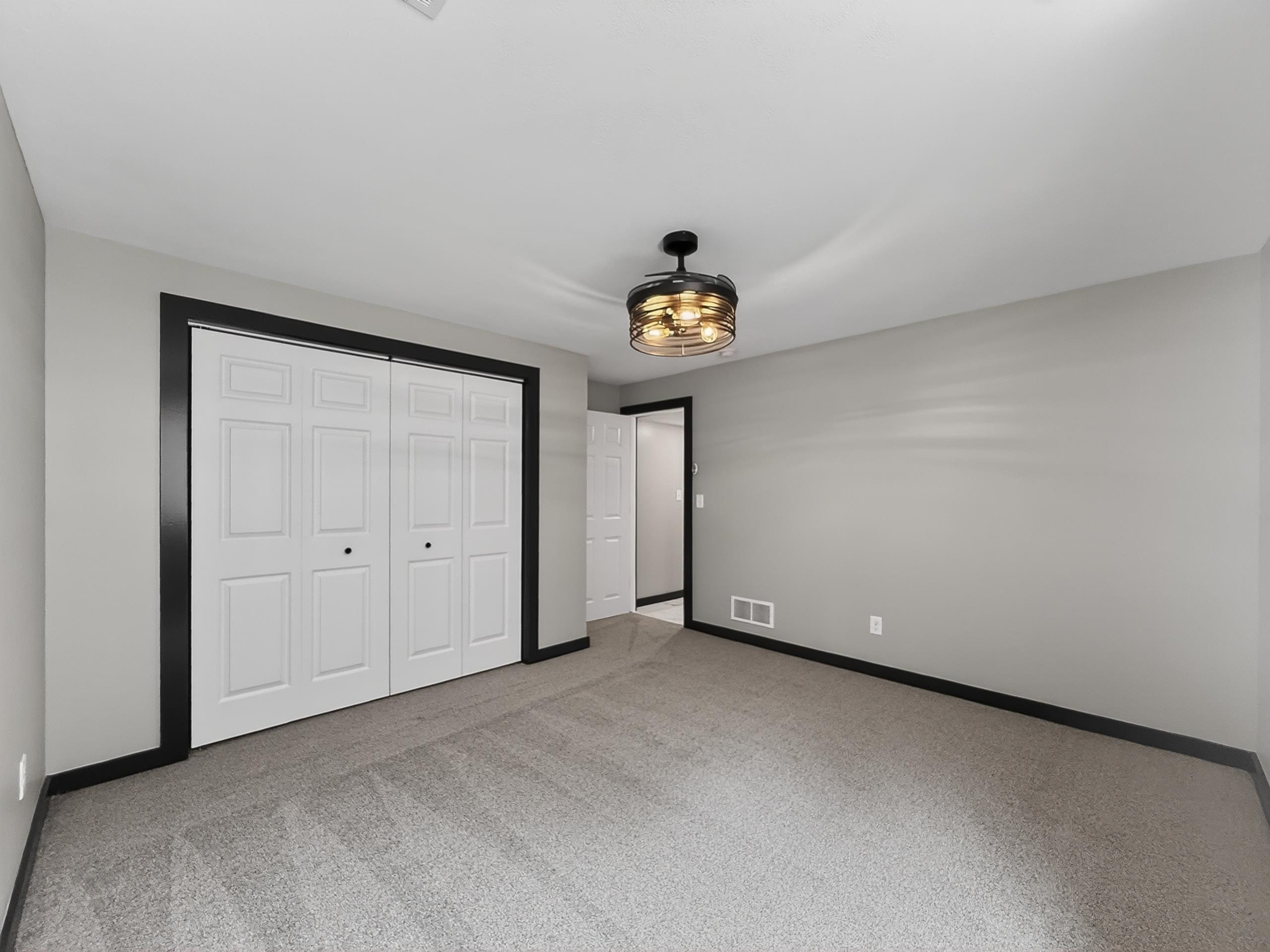 Spacious room featuring neutral carpeting, light gray wall paint, and white trim