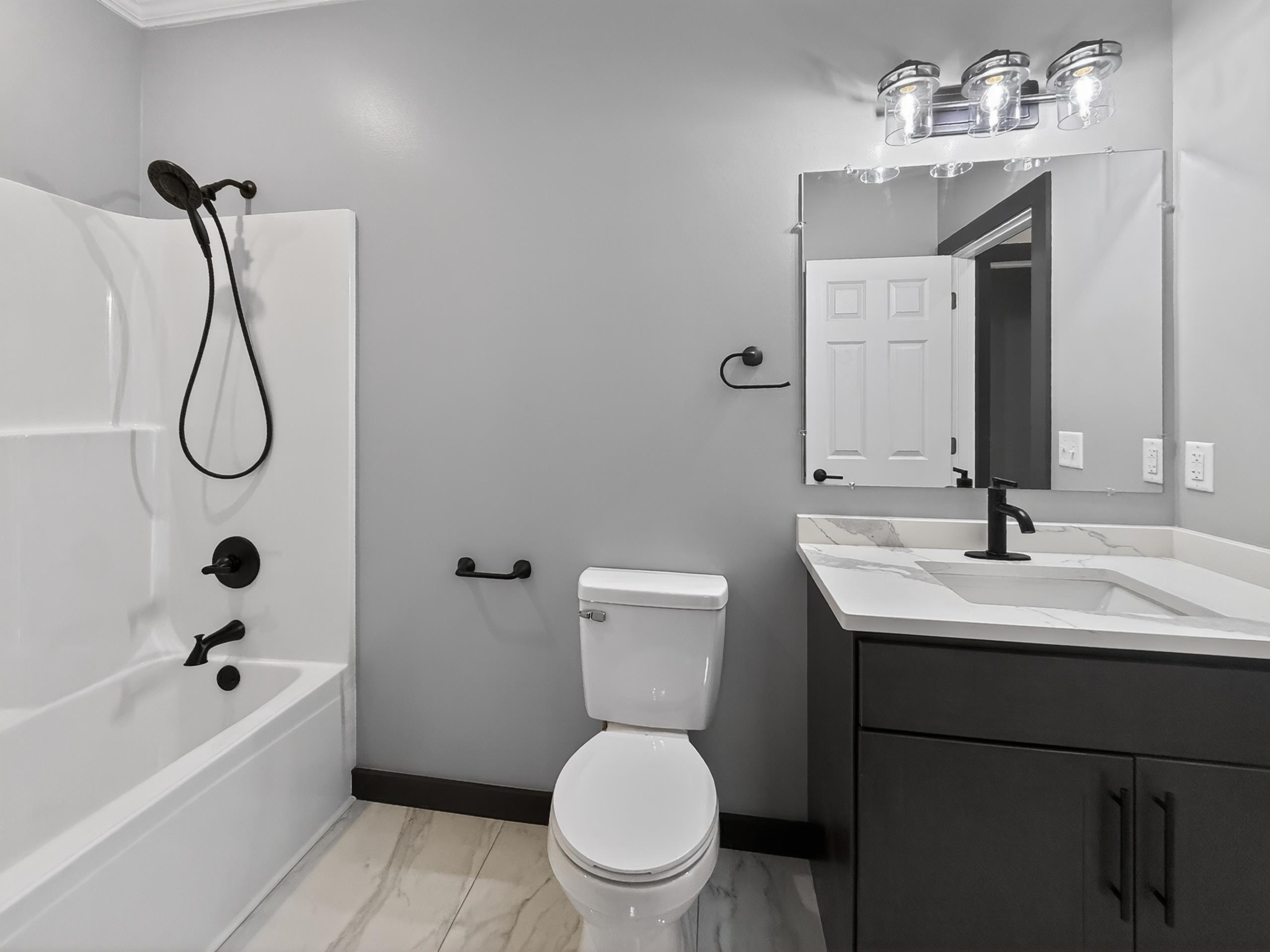 Bathroom featuring a white tub/shower combination with matte black fixtures