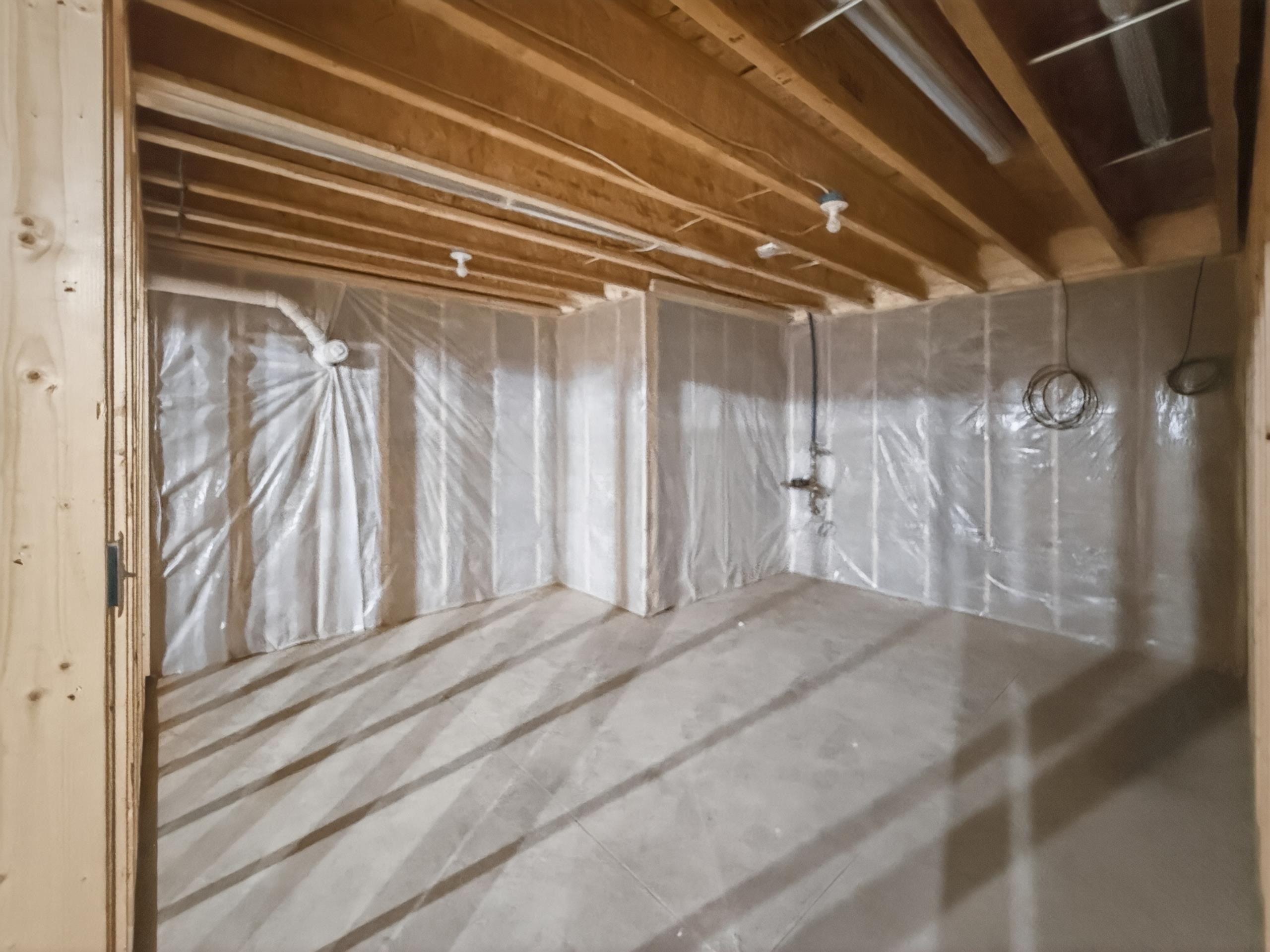 Unfinished basement space with exposed wood joists and concrete flooring