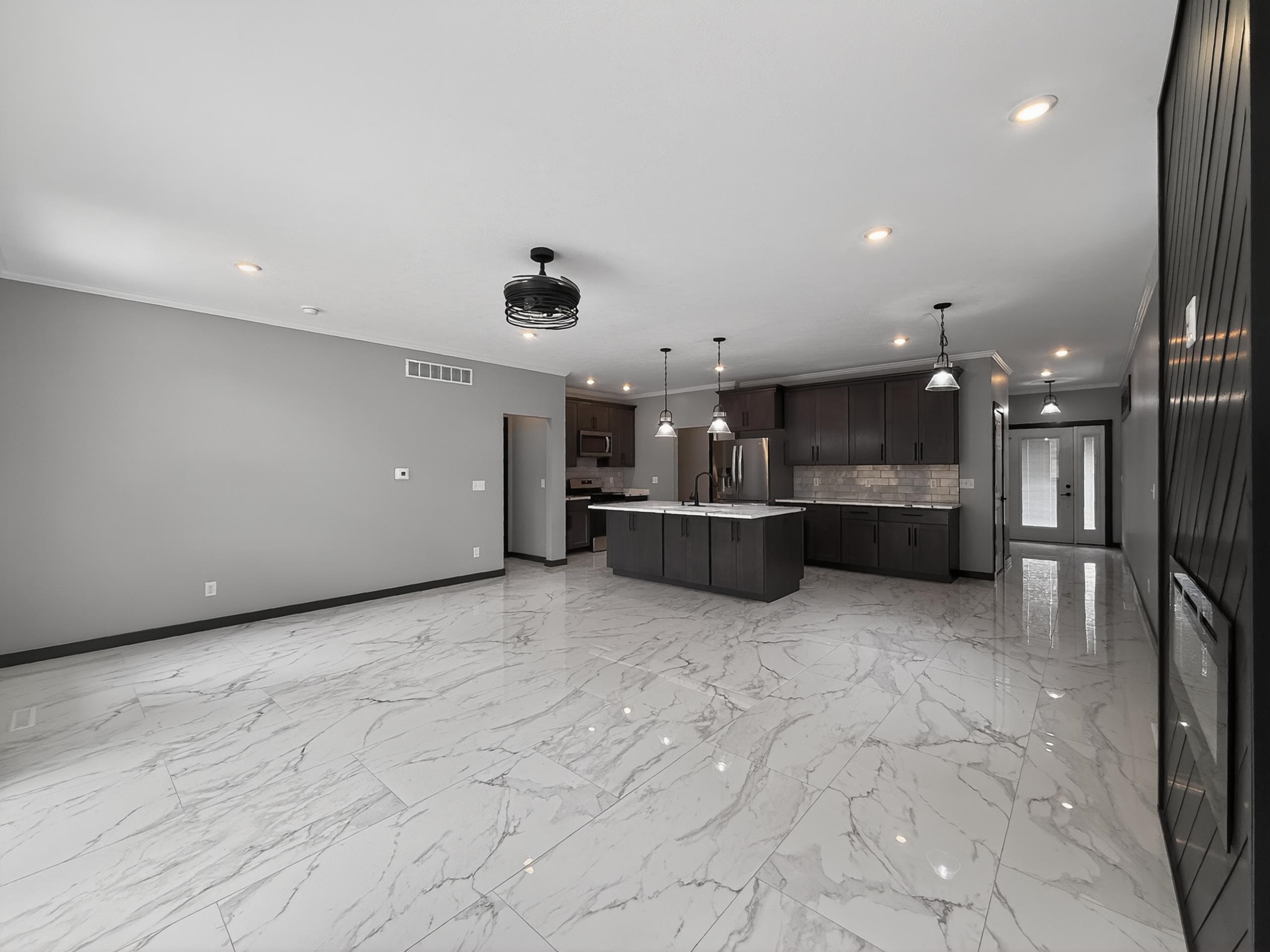 Spacious open-concept living area featuring large format tile flooring, recessed lighting, and a modern ceiling fan