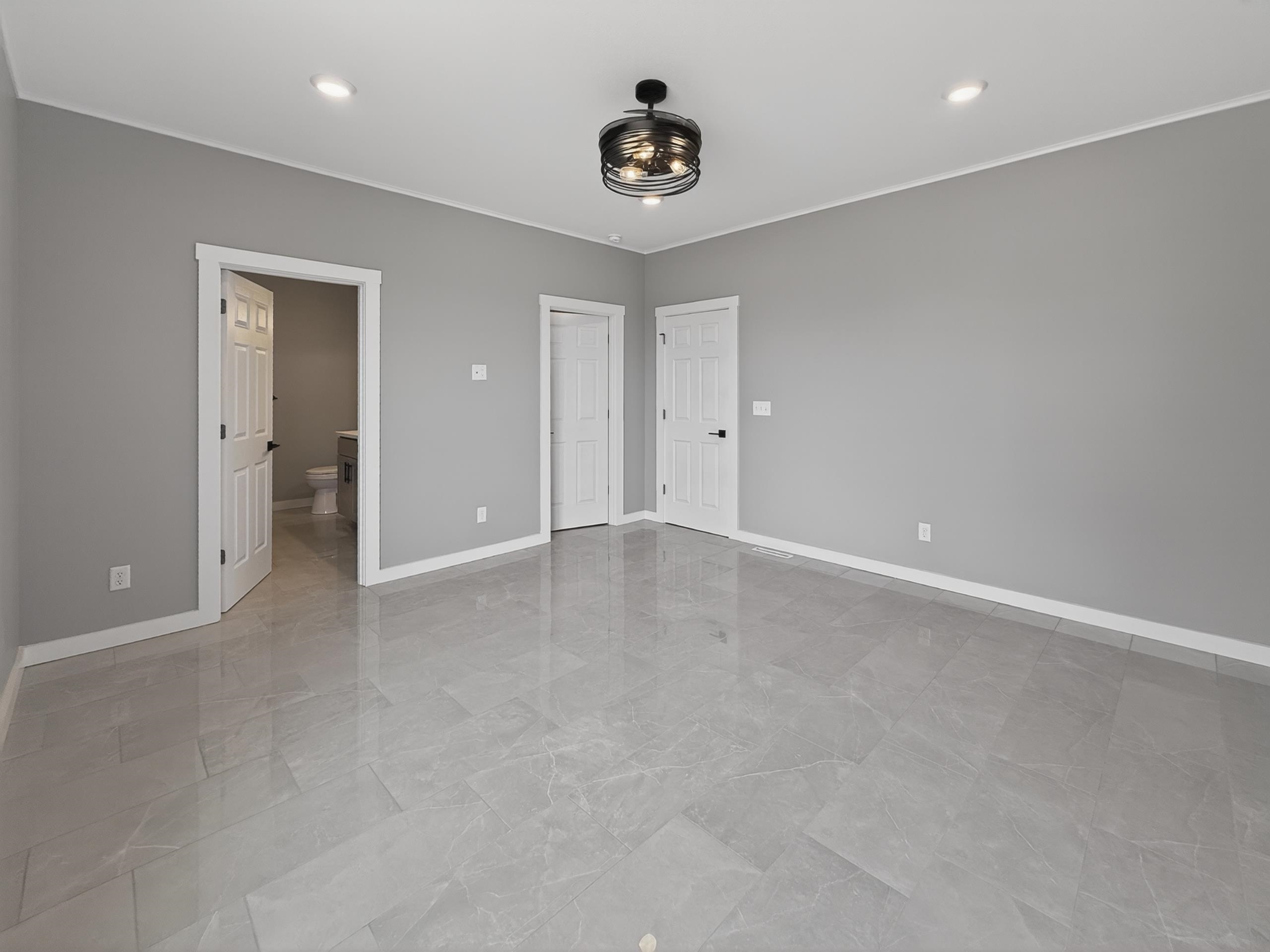 Spacious room featuring large format grey tile flooring, recessed ceiling lighting, a modern ceiling fan with integrated lighting, and neutral wall tones