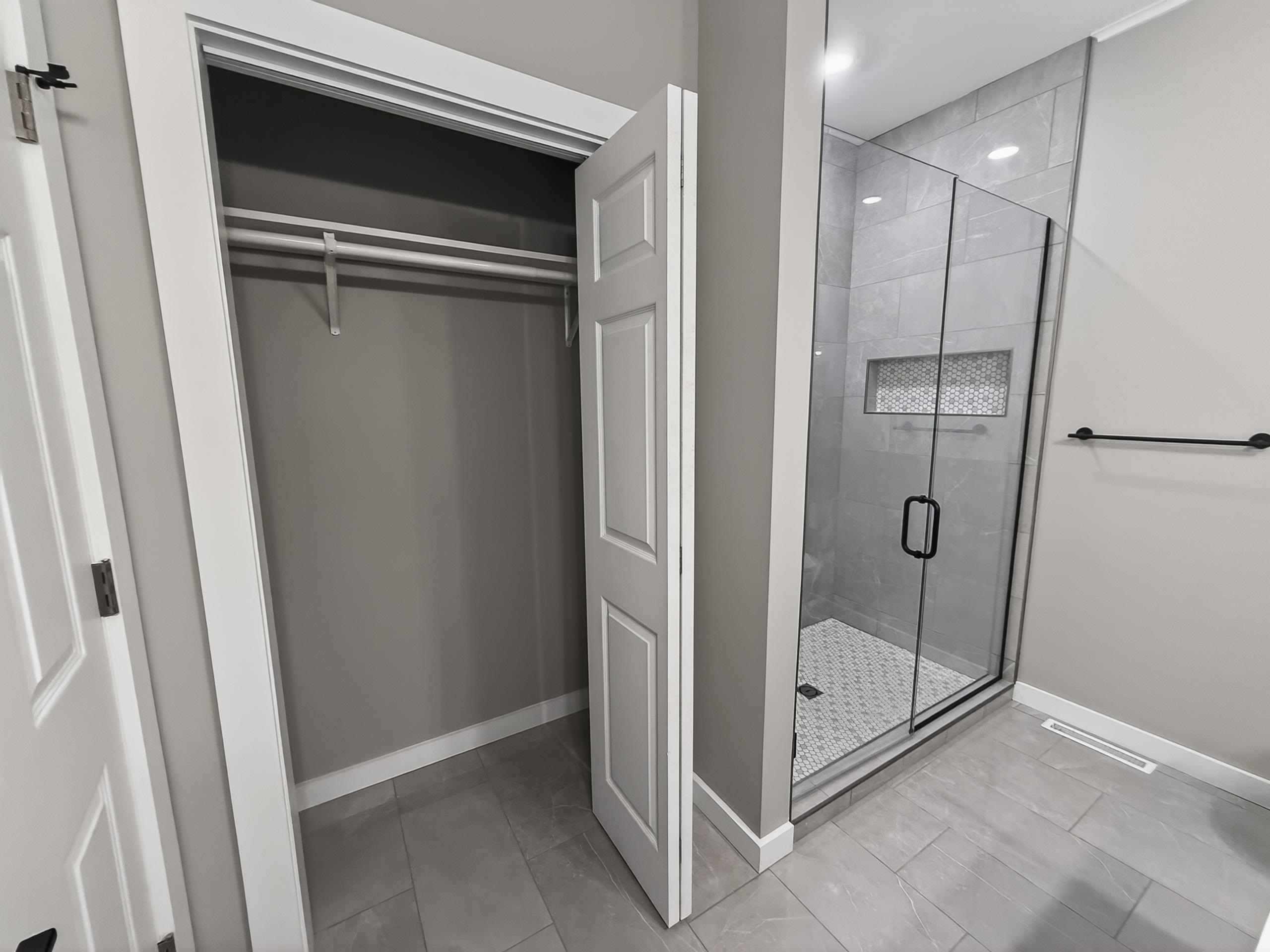 Modern bathroom with a glass-enclosed shower featuring large format tile walls, a mosaic-tiled niche, and a mosaic-tiled shower pan