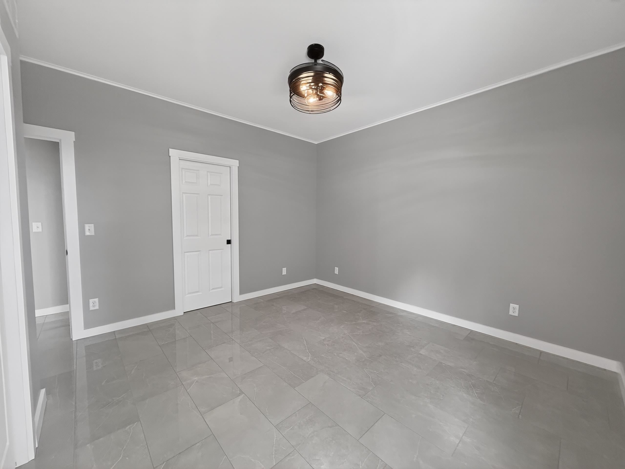 Open room featuring gray walls, light gray tile flooring, white trim, and a contemporary ceiling fixture