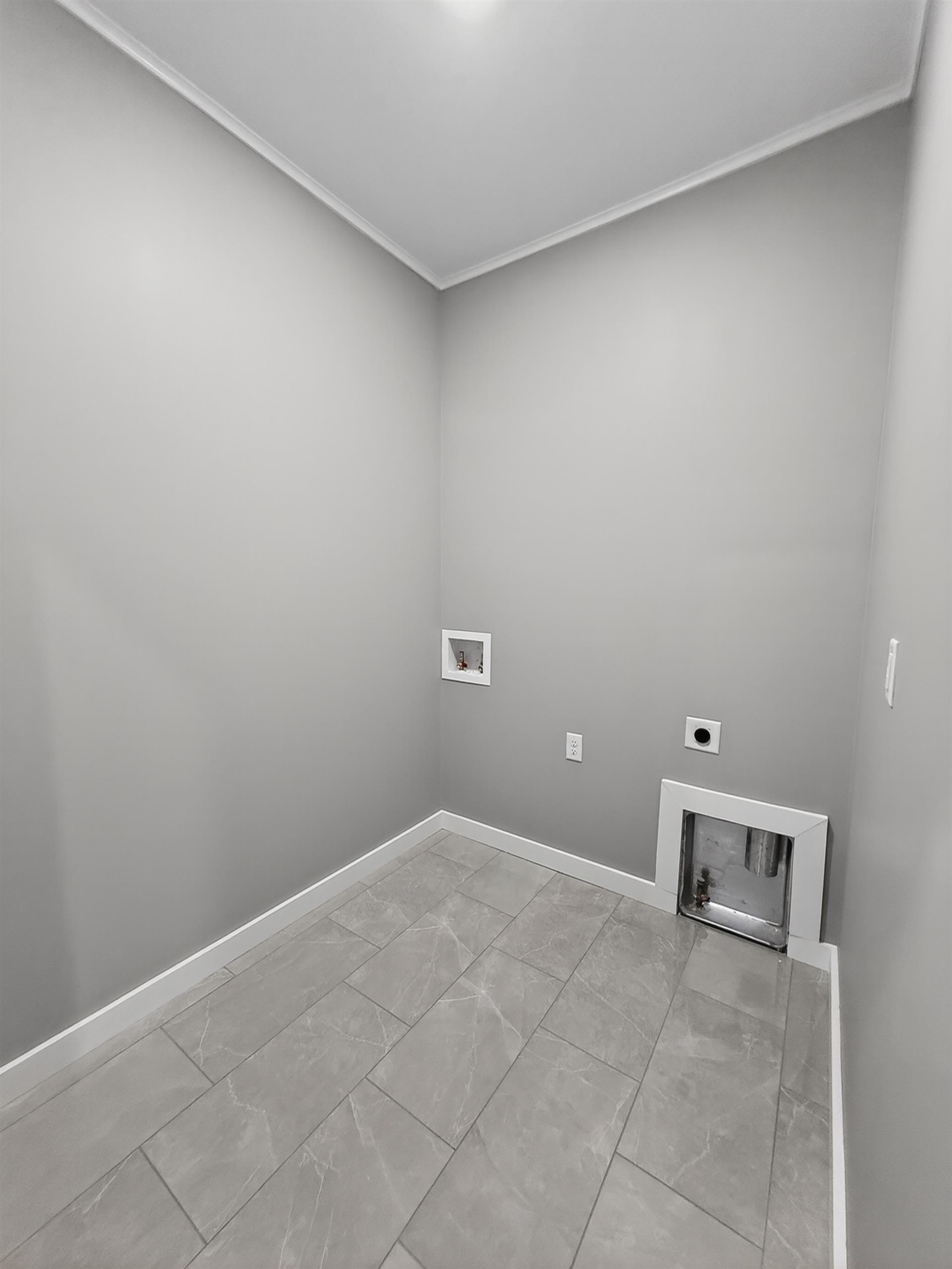 Utility room with gray rectangular floor tiles, white baseboards, and light gray walls