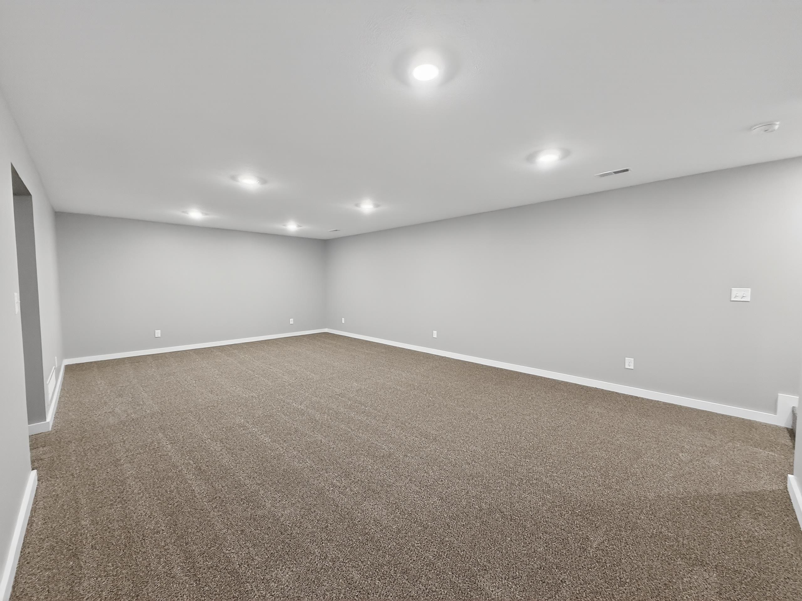 Spacious room featuring neutral carpeting, light gray wall paint, and recessed ceiling lighting