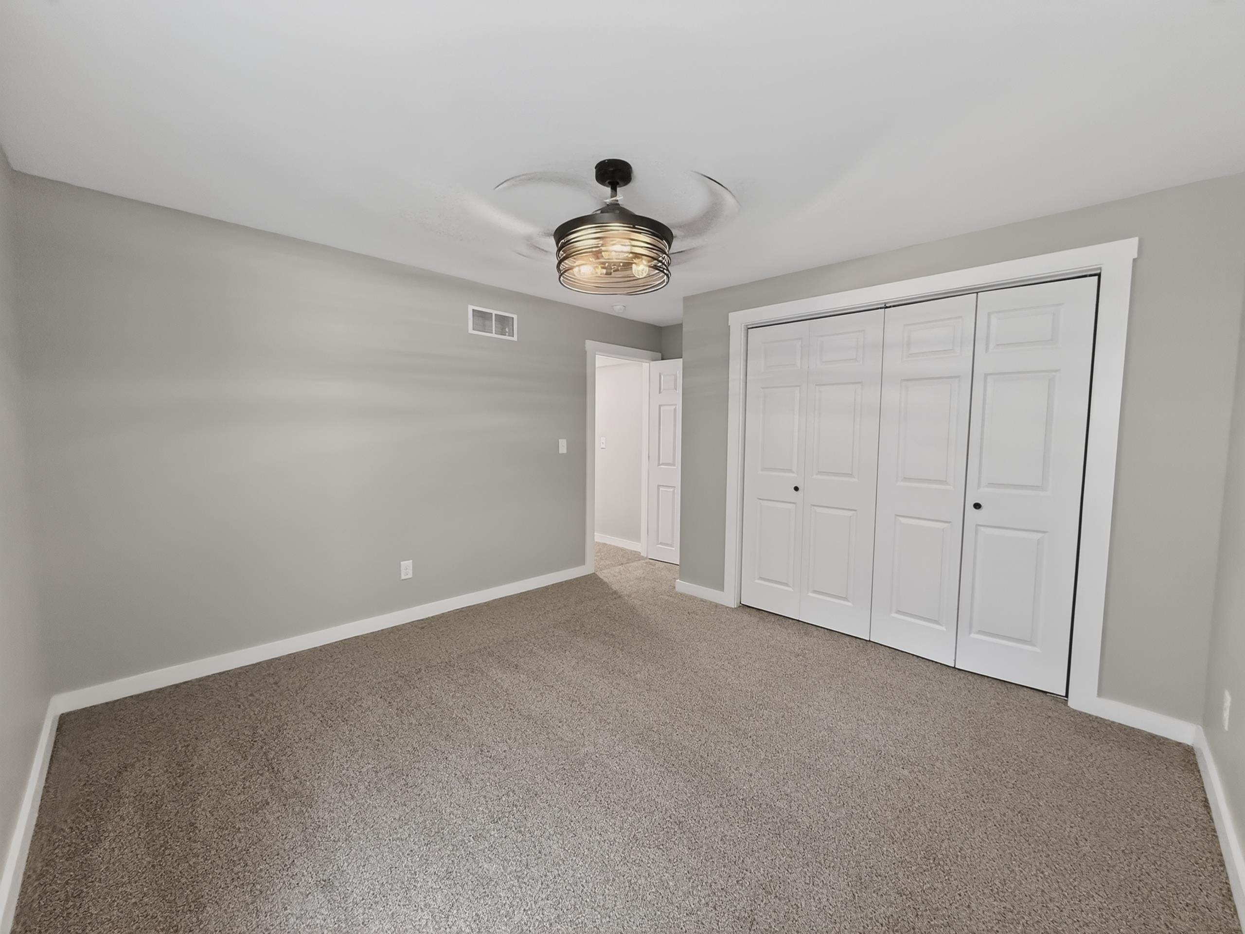 Room featuring neutral grey wall paint, plush carpeting, and white baseboards