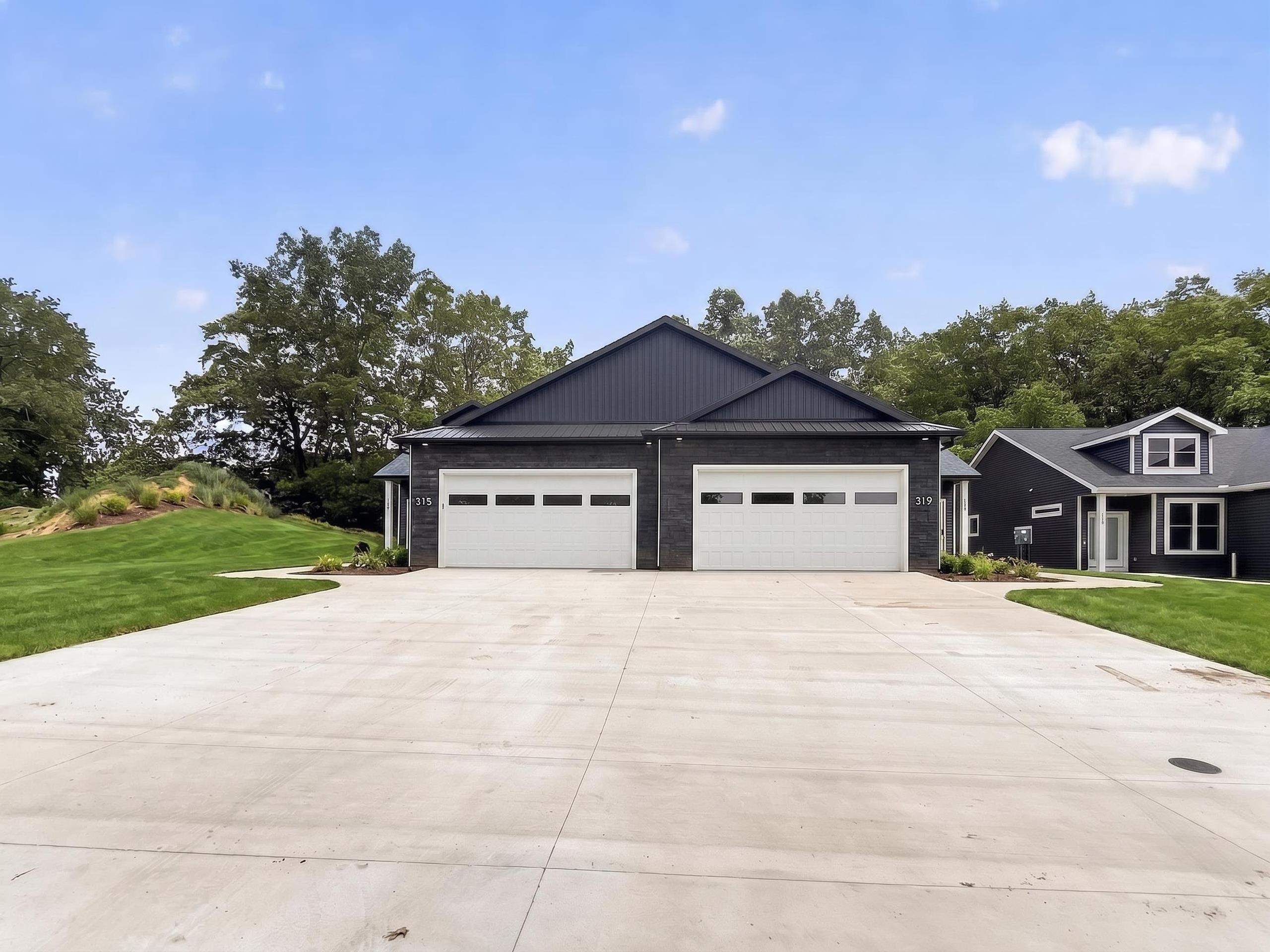 Contemporary duplex featuring dark brick and vertical siding