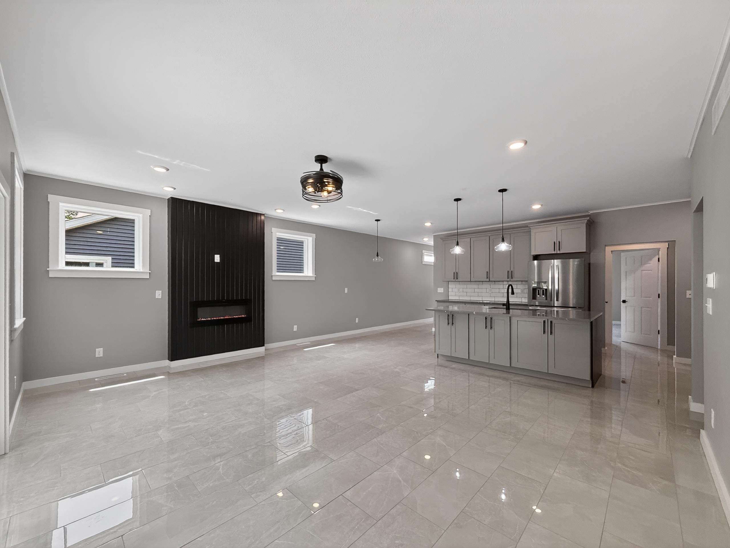 Open-concept living area featuring a kitchen island with pendant lighting, stainless steel refrigerator, and recessed lighting throughout