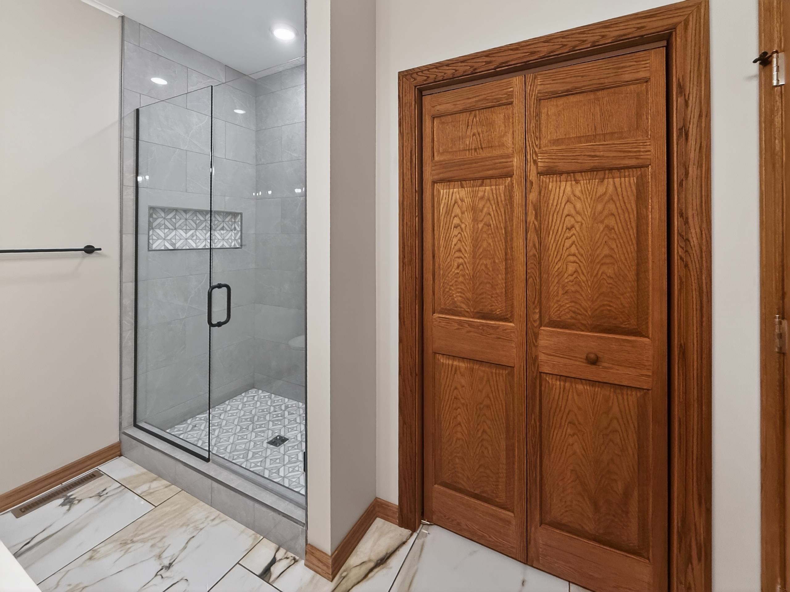 Walk-in shower featuring a clear glass enclosure and black hardware