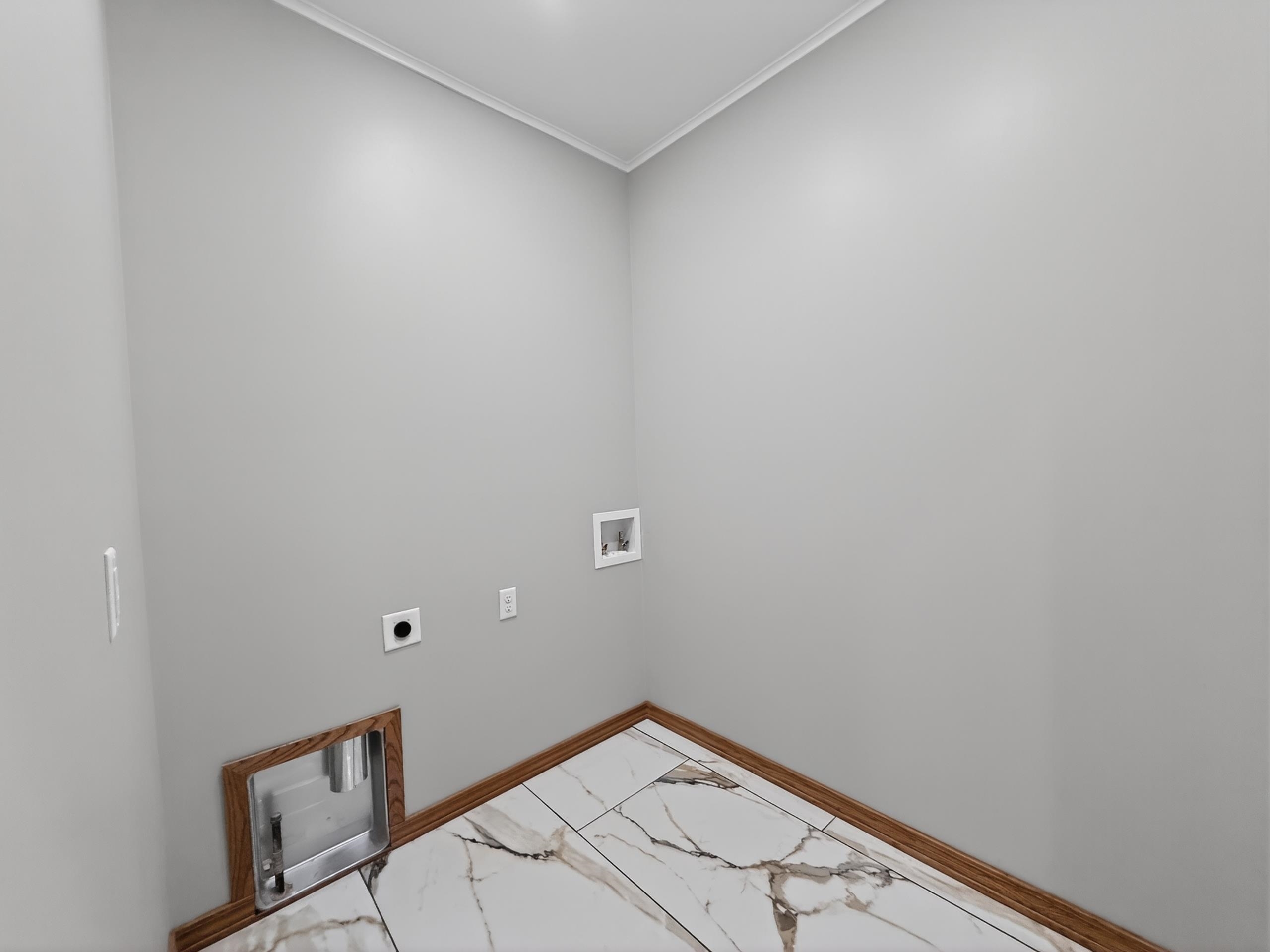 Utility room featuring wood-finish baseboards, light gray walls, and white crown molding