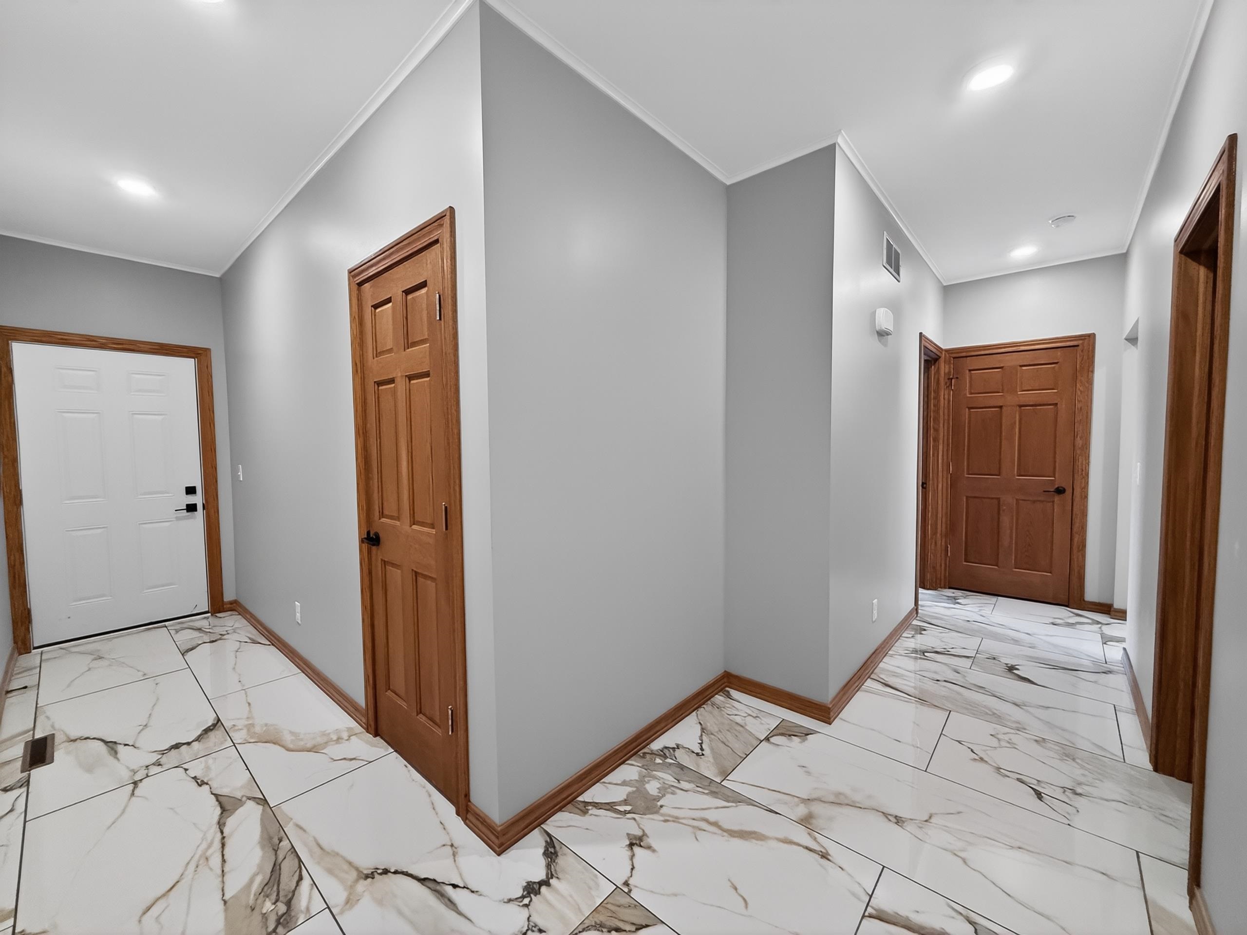 Entryway featuring large format marble-look tile flooring, light gray walls, recessed lighting, and natural wood trim and doors